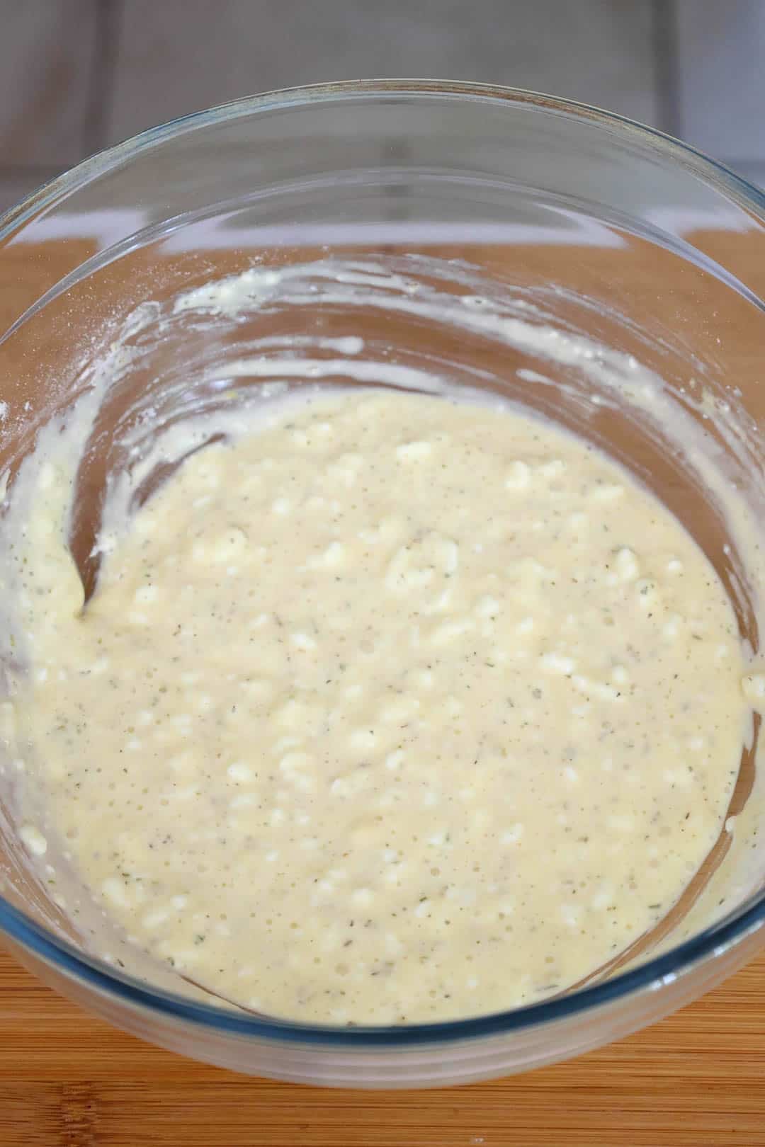 A glass bowl with uncooked pizza crust batter.
