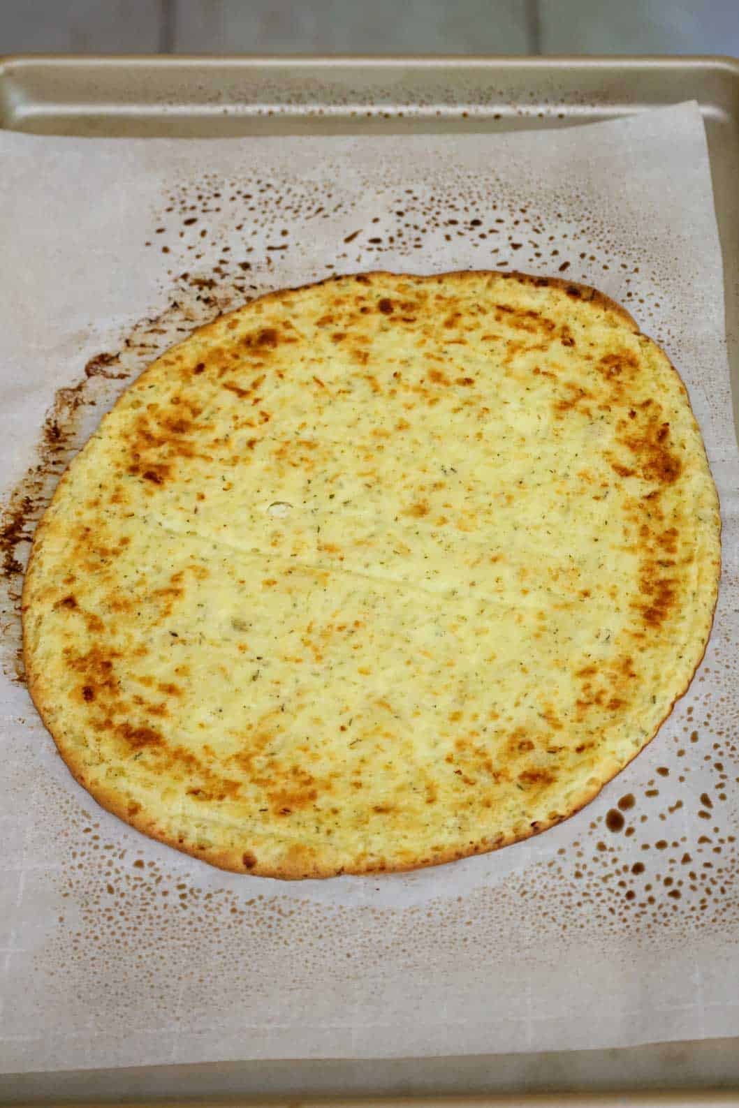 A browned pizza crust on a baking sheet.