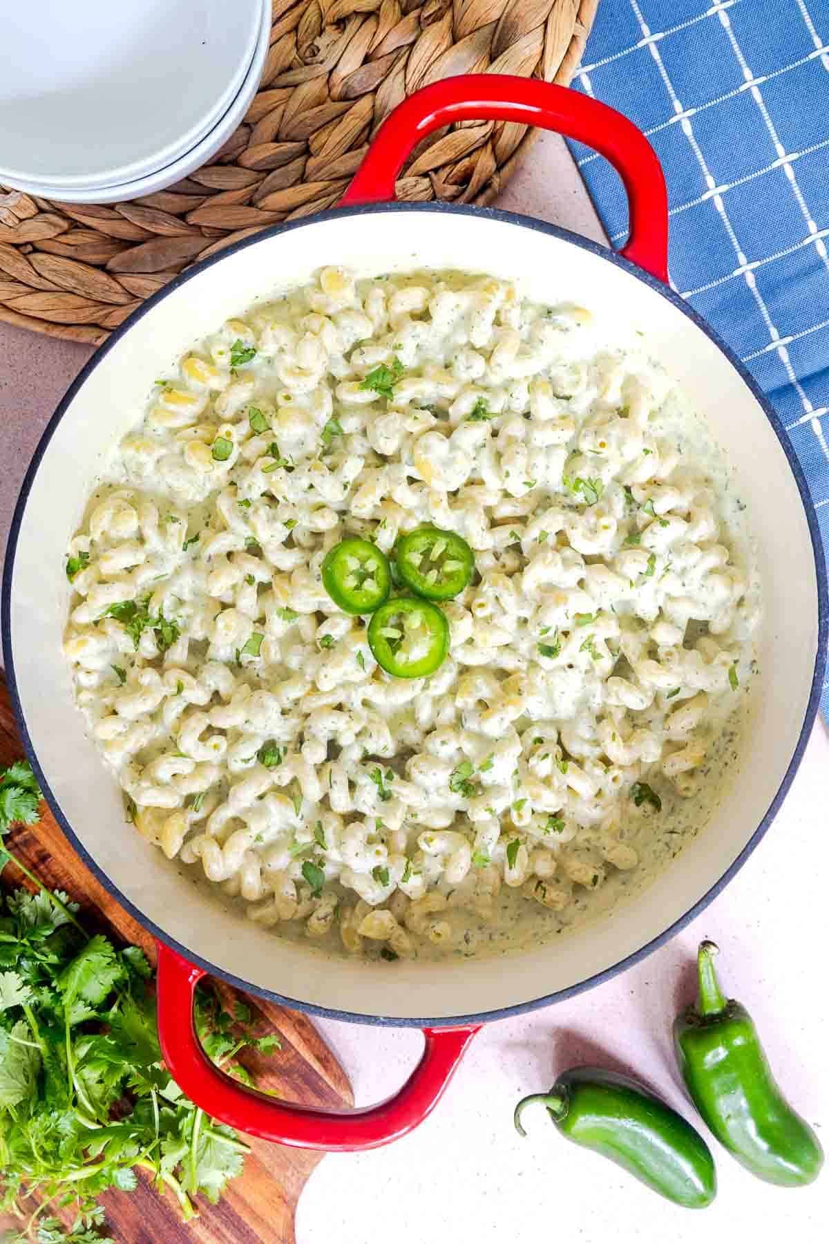 Cooked jalapeño pasta in a pot coated in a creamy sauce, topped with sliced jalapeños and cilantro.