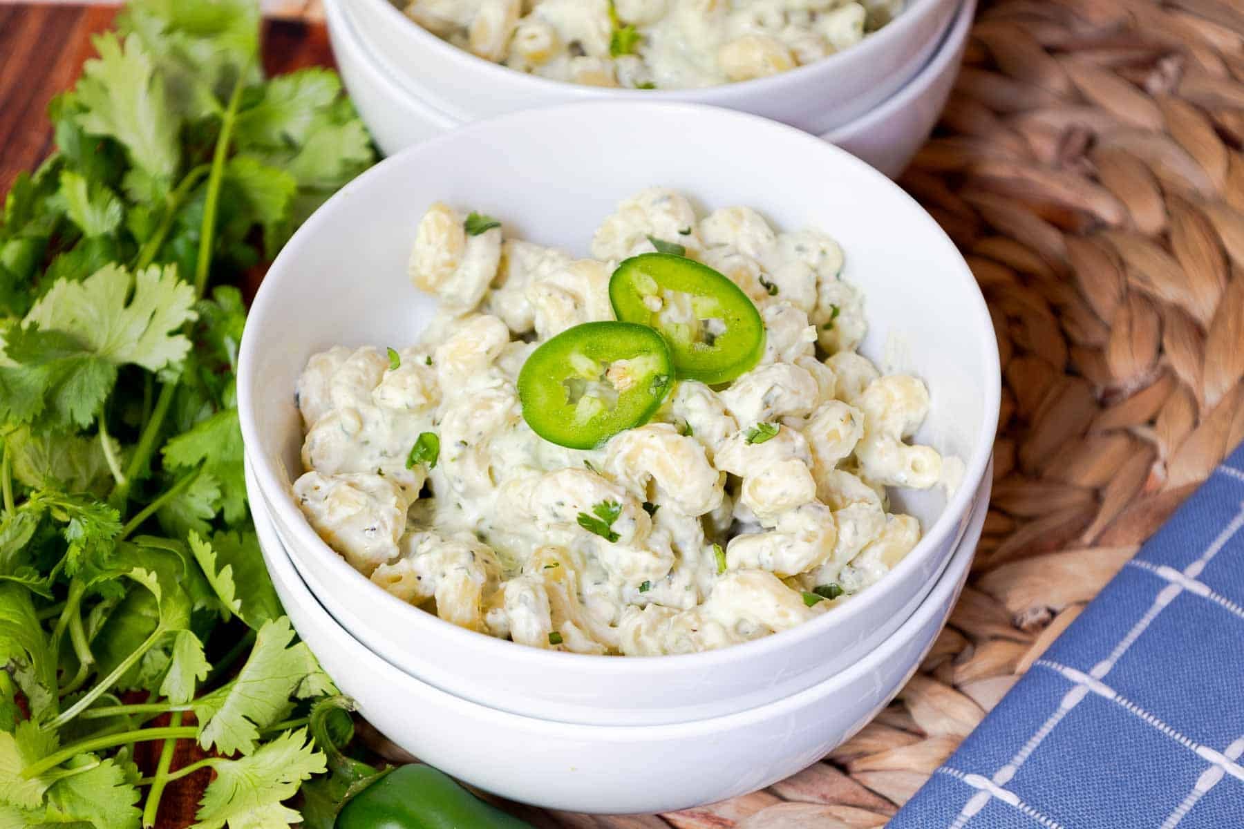 Two bowls of creamy pasta topped with sliced jalapeños.