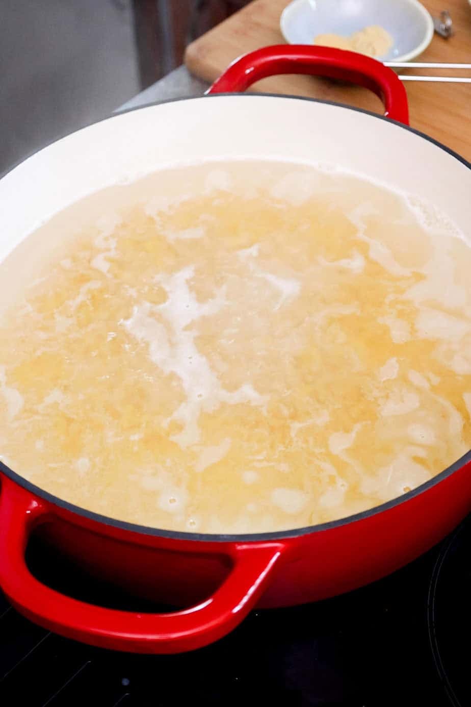 Elbow macaroni boiling in a large pot.