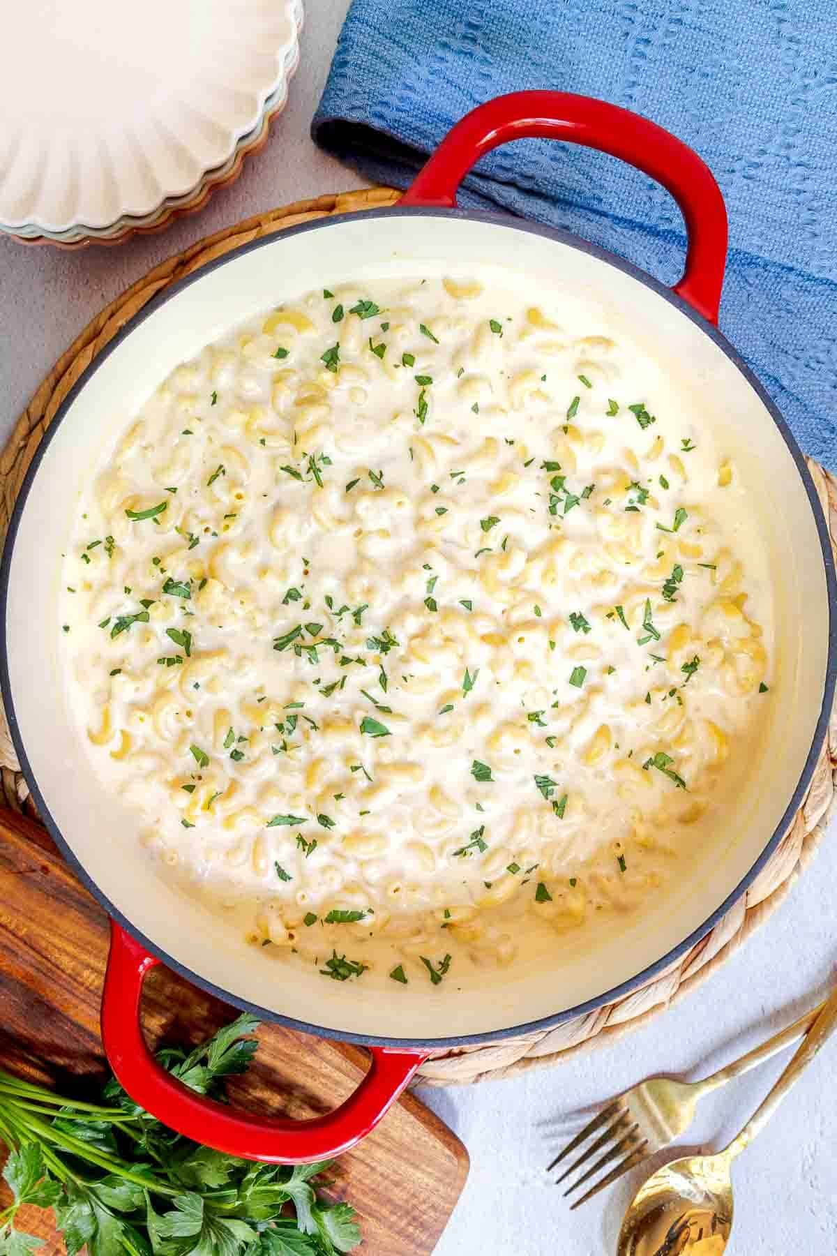 A pot of white cheddar mac and cheese topped with chopped parsley.
