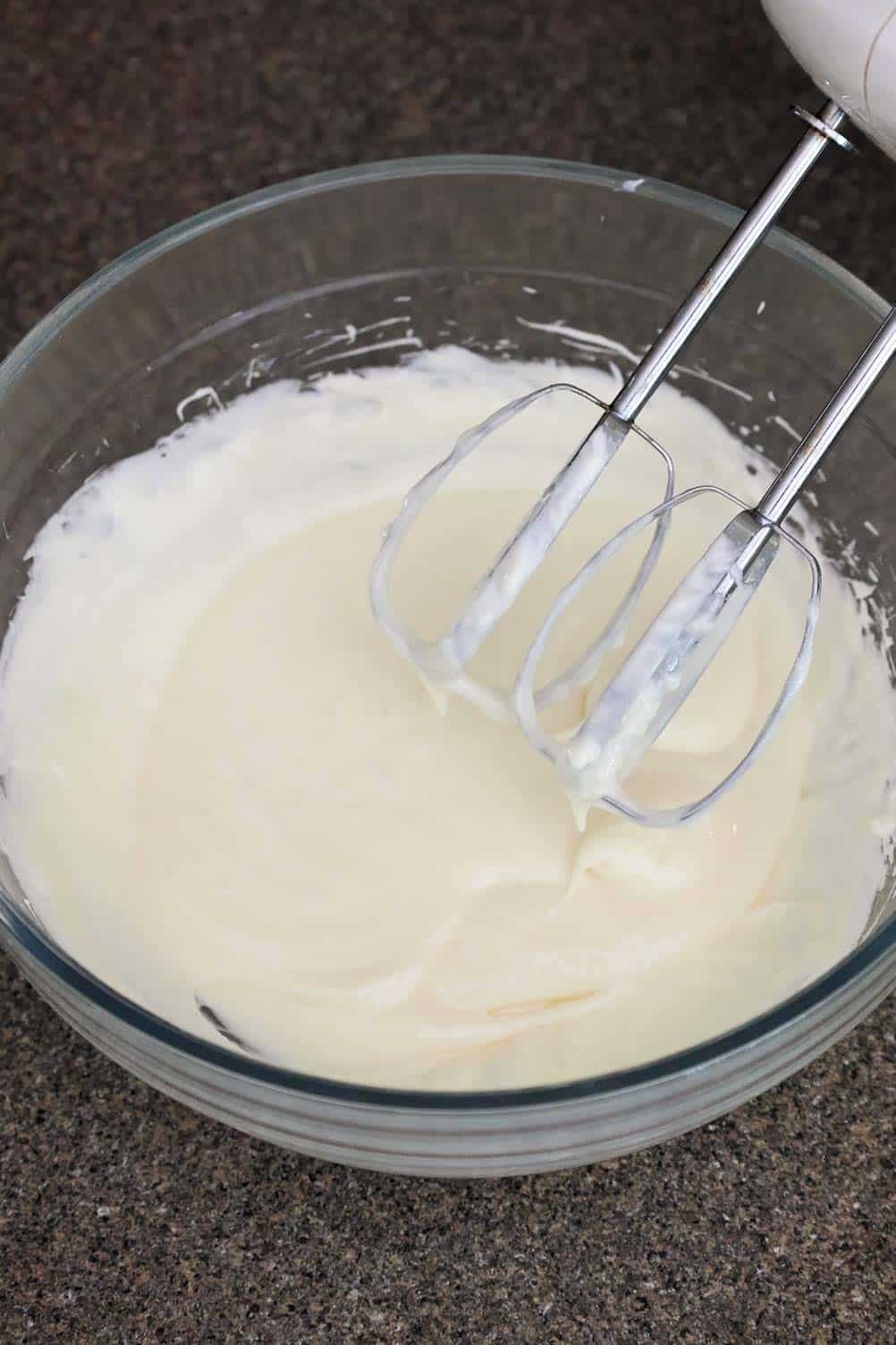 A bowl of fruit dip in mid-mixing, showing a smooth and creamy texture.