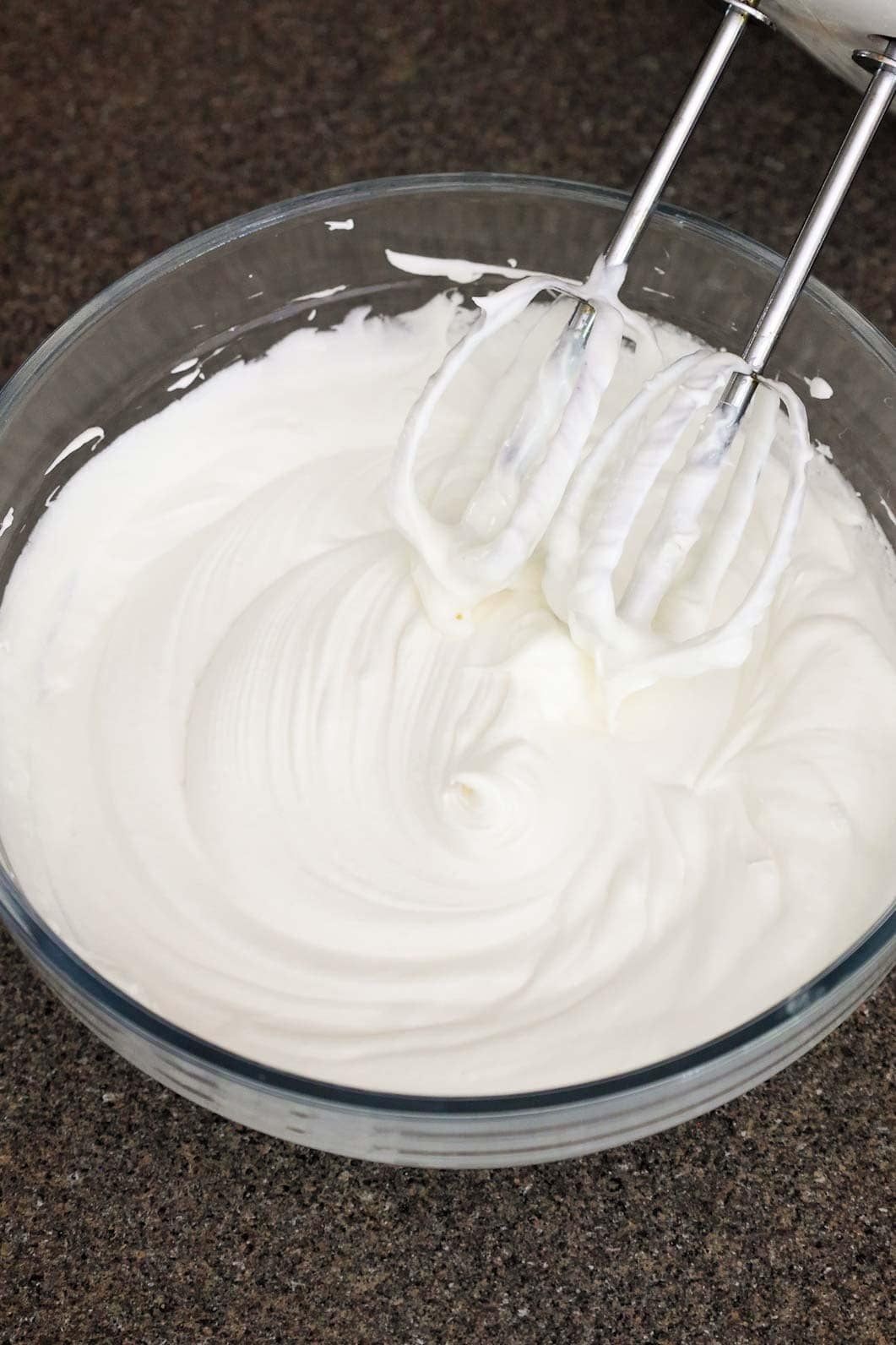 Final whipped fruit dip in a bowl with a fluffy and airy consistency, beaters from an electric mixer resting above it.