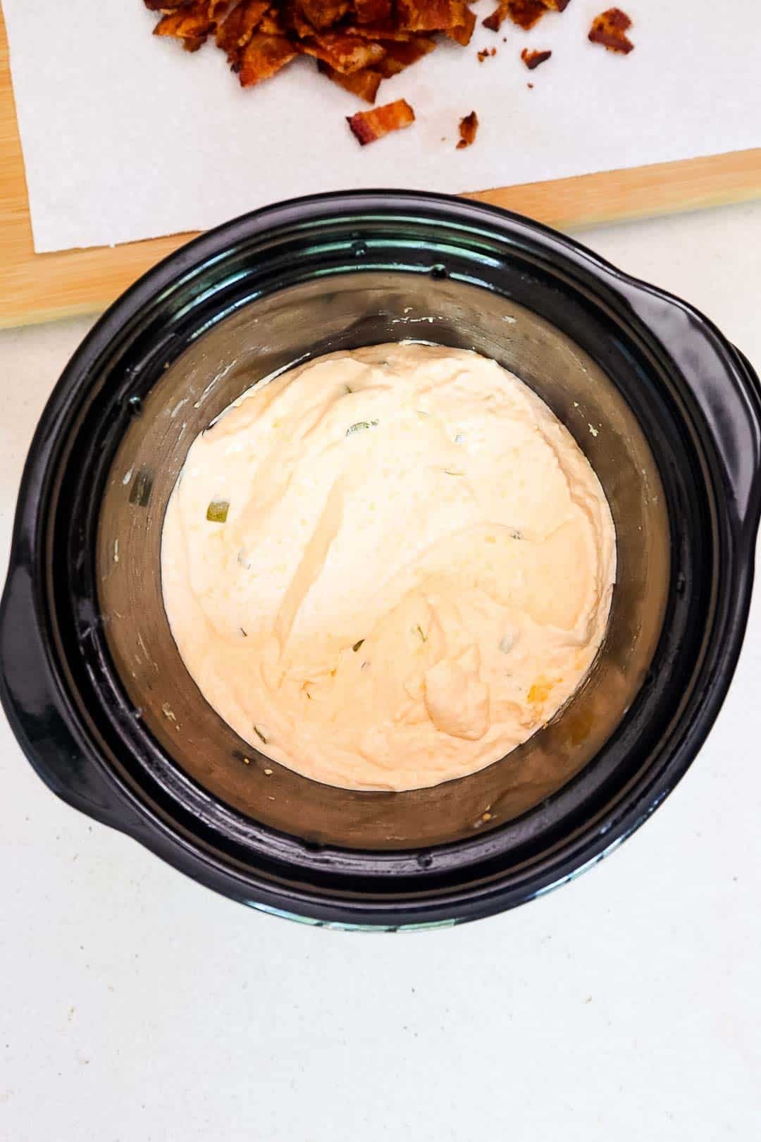 Smooth, creamy jalapeño popper dip inside a slow cooker.