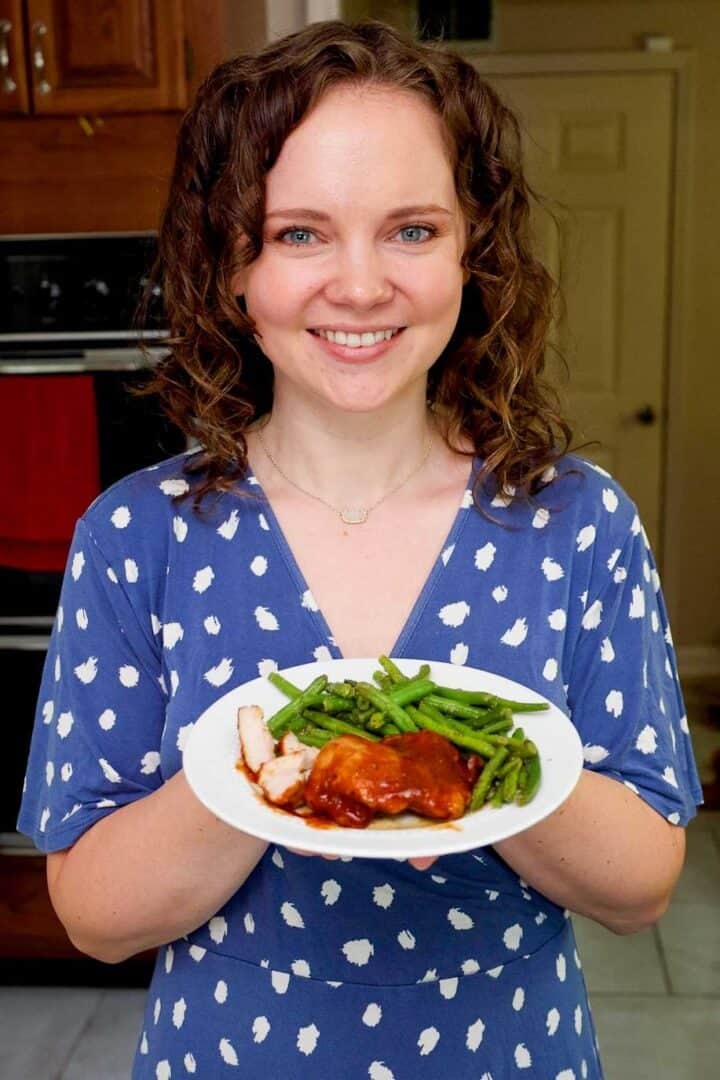 Kelsey Smith holding a plate with BBQ chicken thighs and green beans.