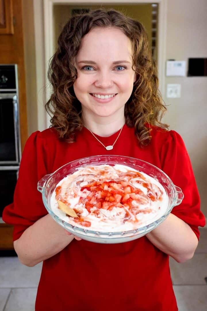 Kelsey Smith holding a pie dish of strawberry cheesecake dip.