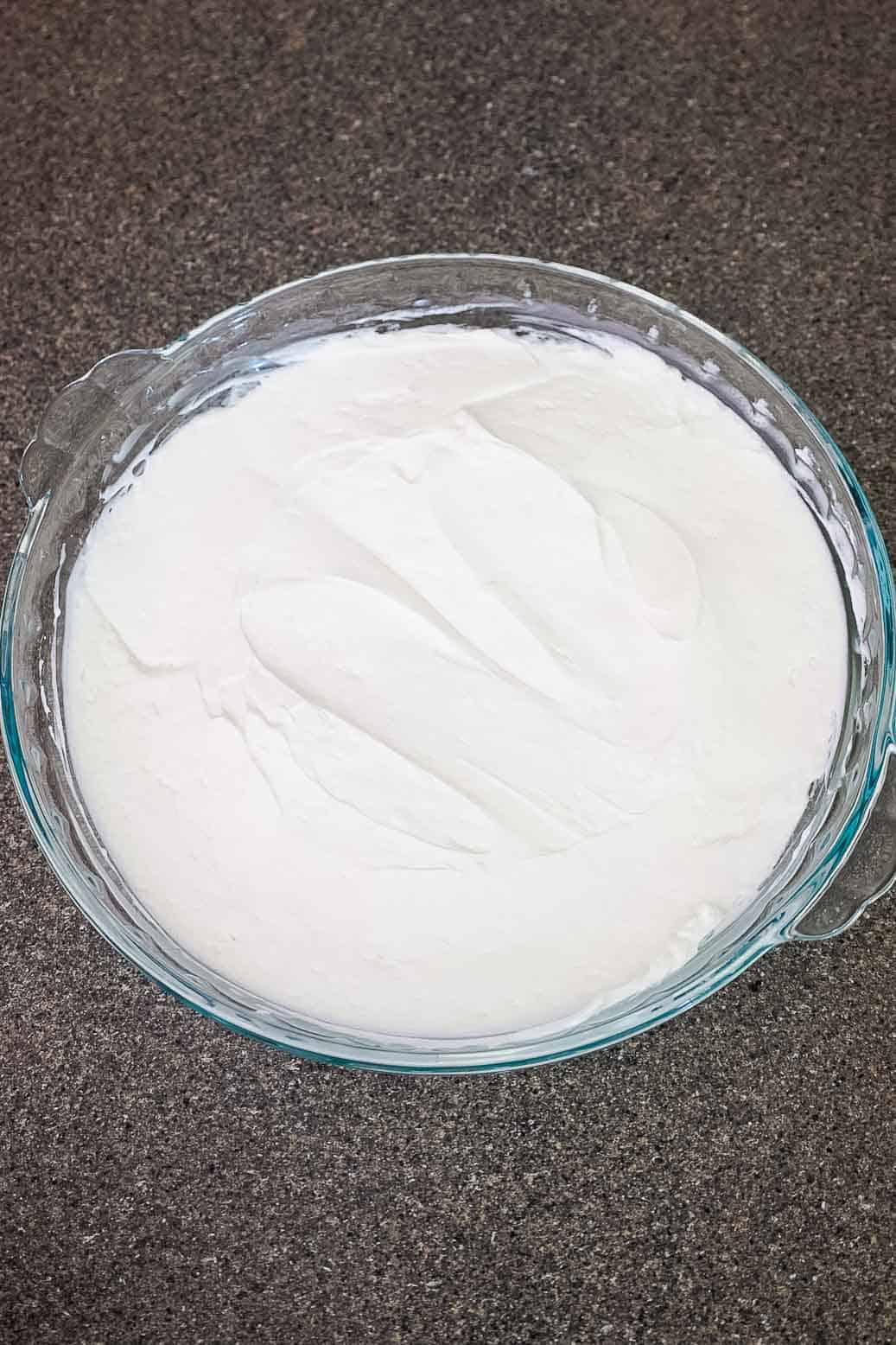 Pie dish filled with cream cheese and whipped cream mixture, spread evenly.