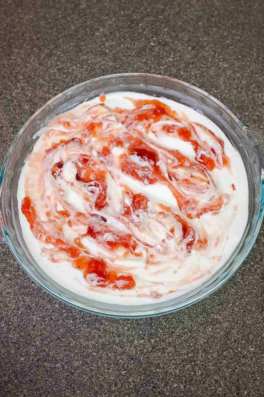 Cream cheese dip mixture with strawberry jam swirled into the top in a marble pattern.