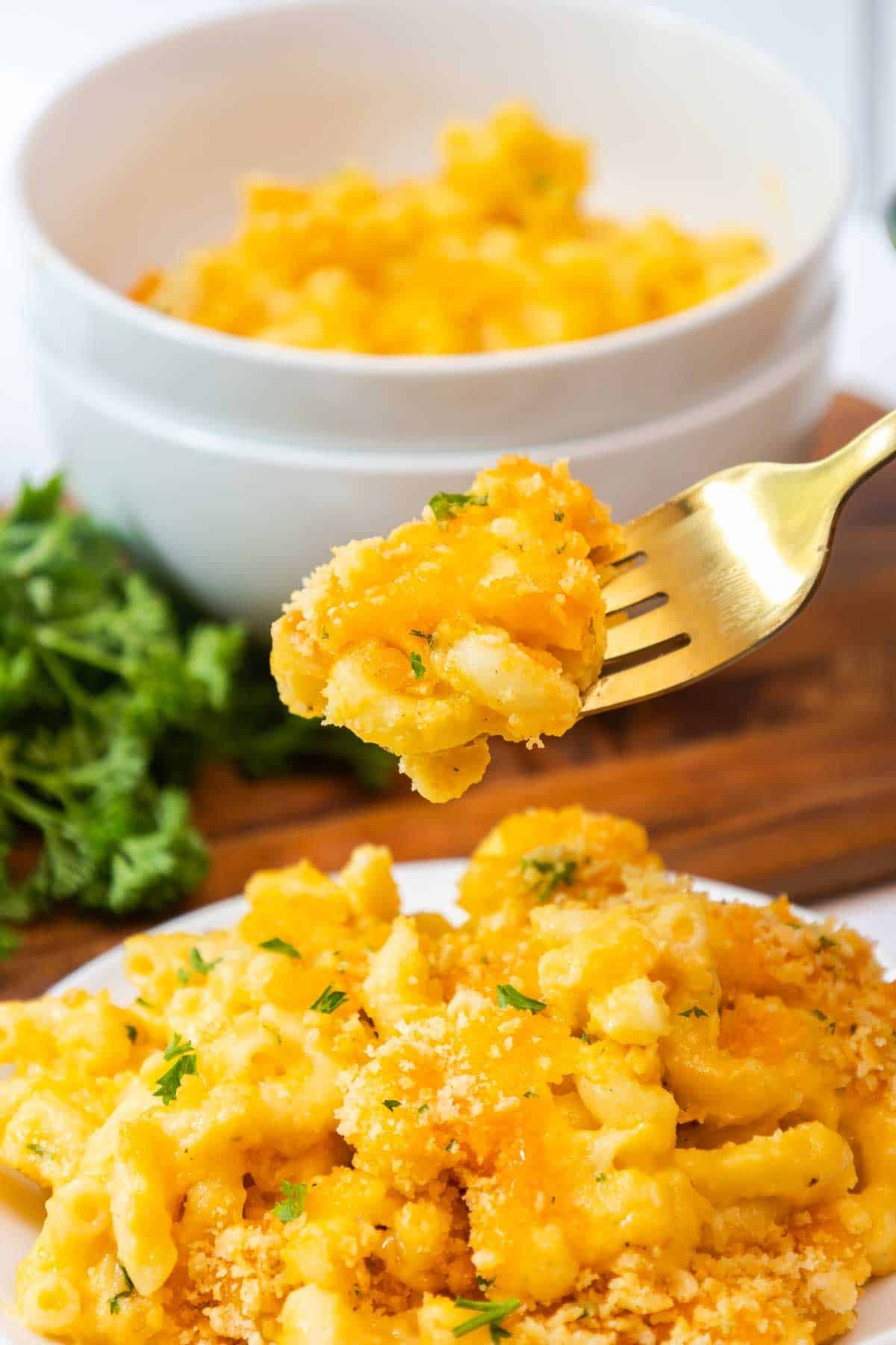 A fork lifting a cheesy bite of old fashioned baked mac and cheese.