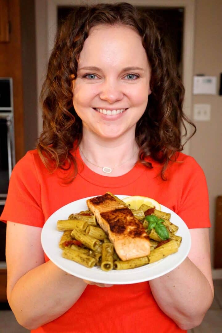 Kelsey Smith holding a plate of salmon pesto pasta.