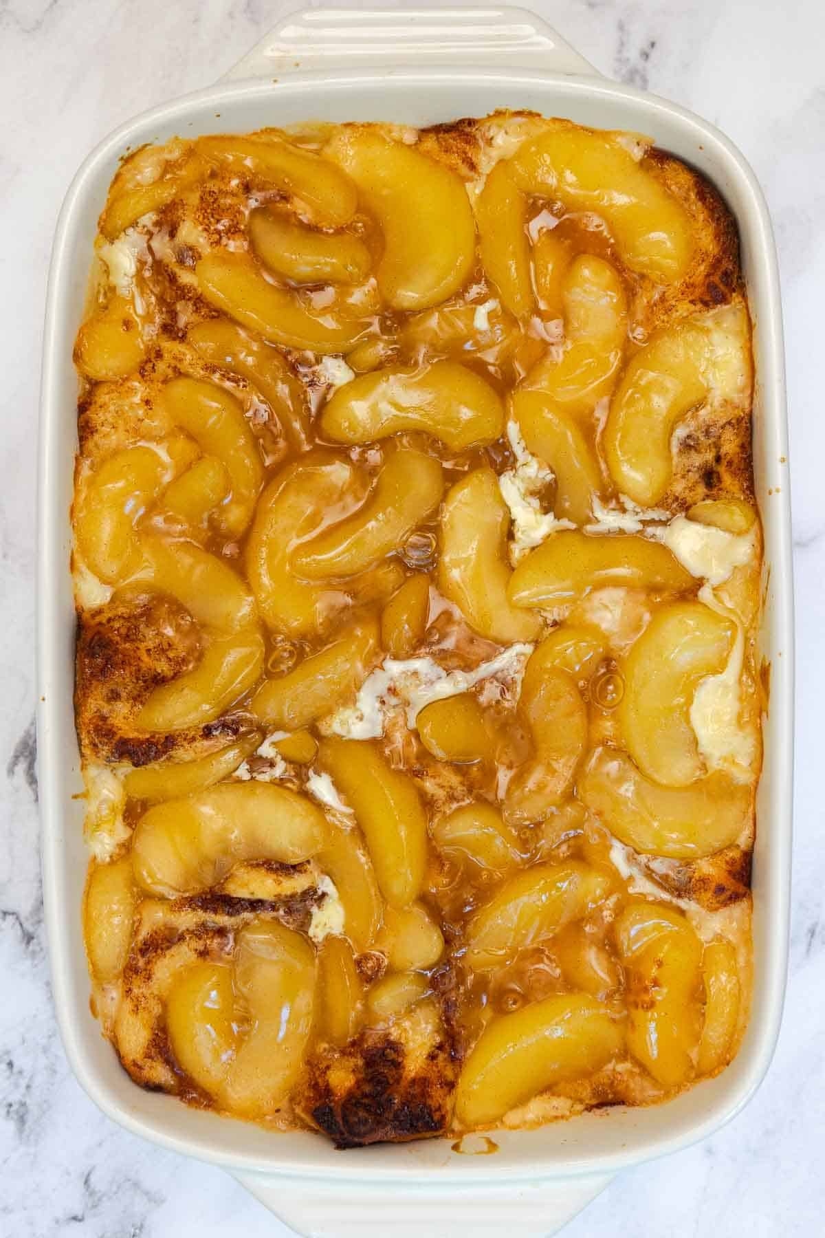 Baked cinnamon roll casserole fresh out of the oven, topped with apple filling.