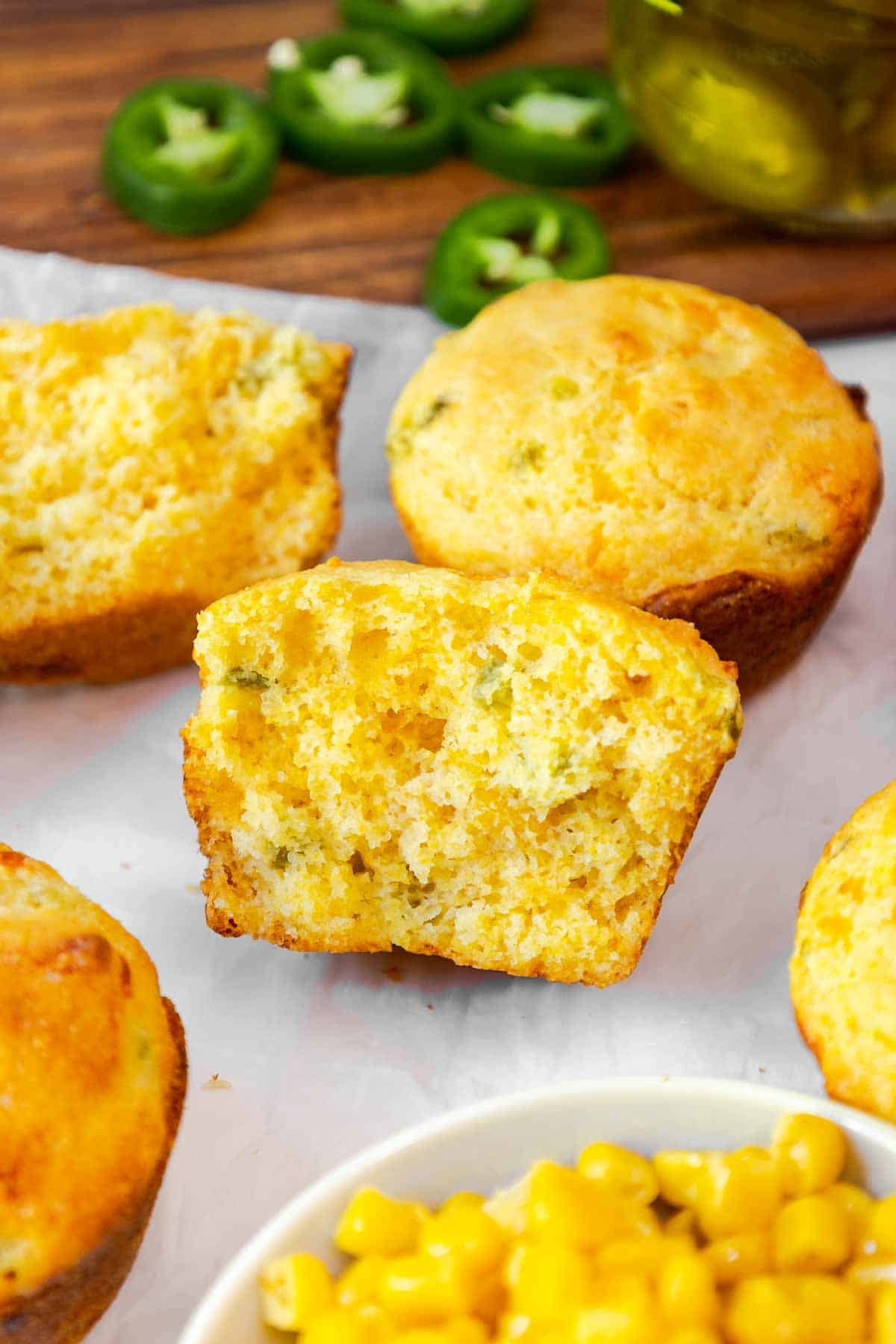 A halved jiffy jalapeño cornbread muffin showing its fluffy, cheesy interior with visible bits of jalapeño and corn.