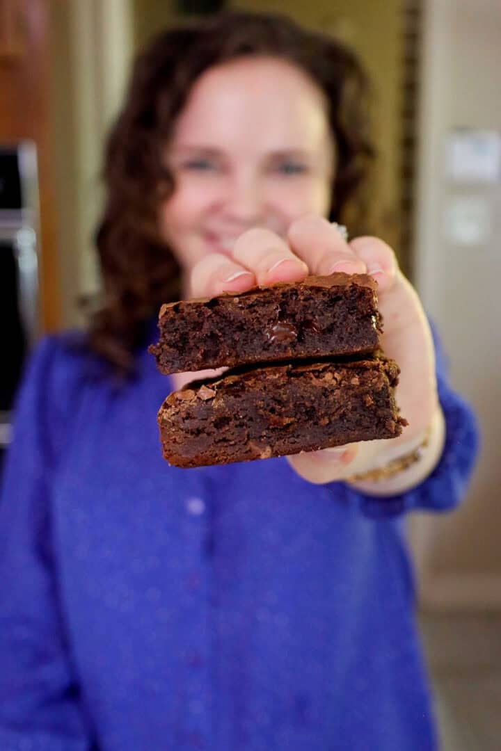 Kelsey Smith holding two brownies stacked together toward the camera.