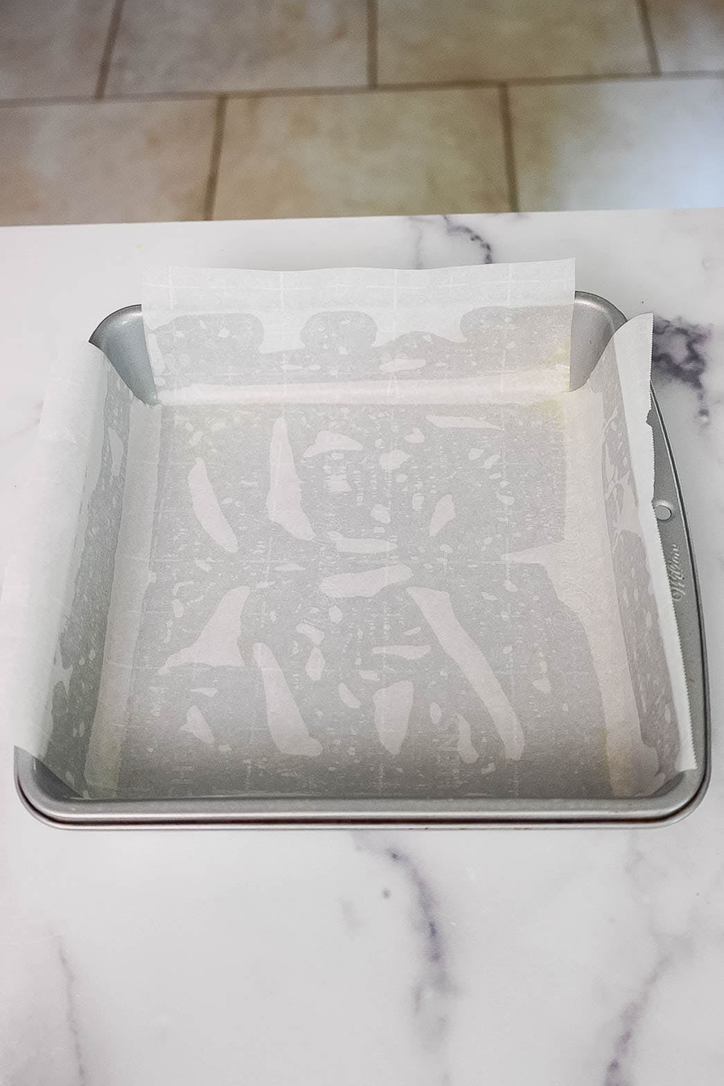 Square metal baking pan lined with parchment paper.