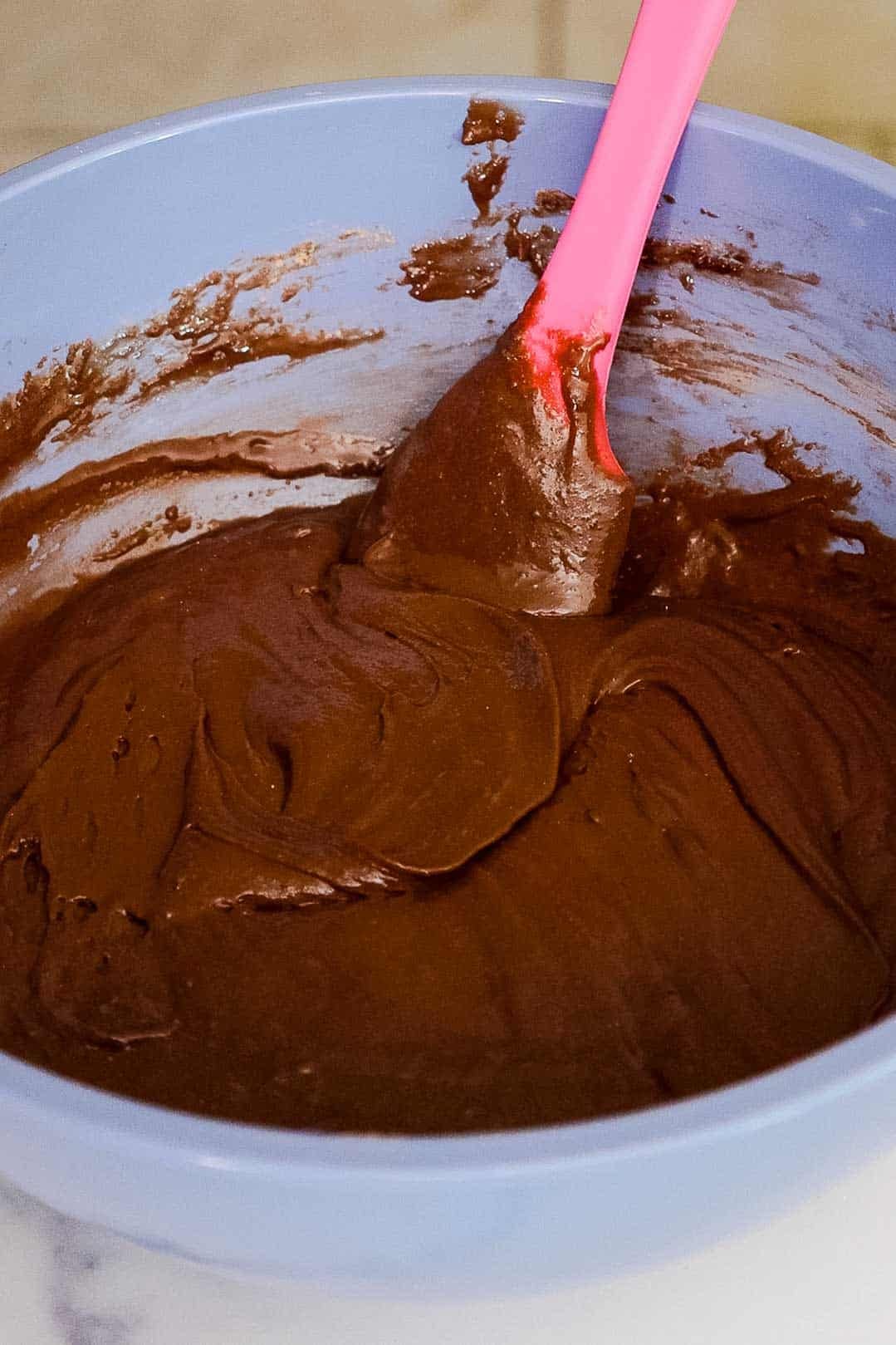 Thick chocolate brownie batter in a medium mixing bowl.