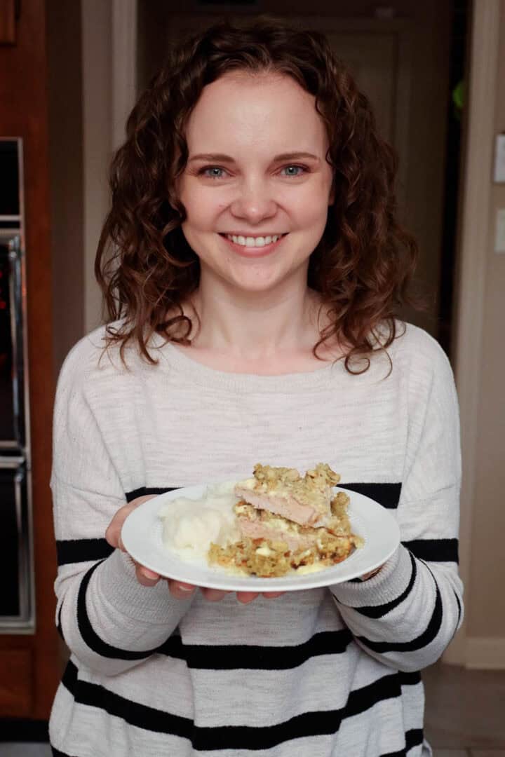 Kelsey Smith holding a plate with pork chops and stuffing.