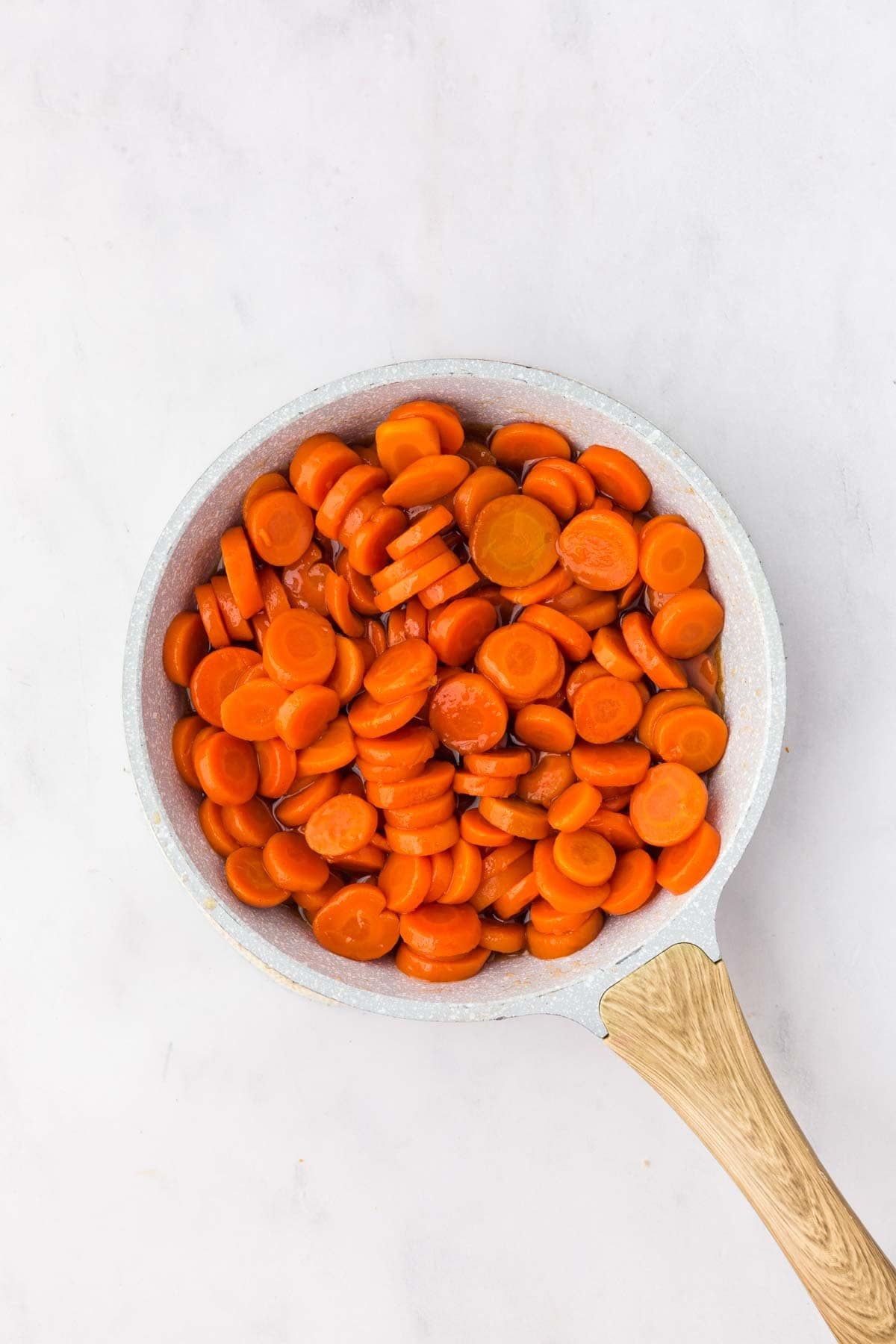 Canned carrot in a skillet coated with brown sugar and honey glaze.