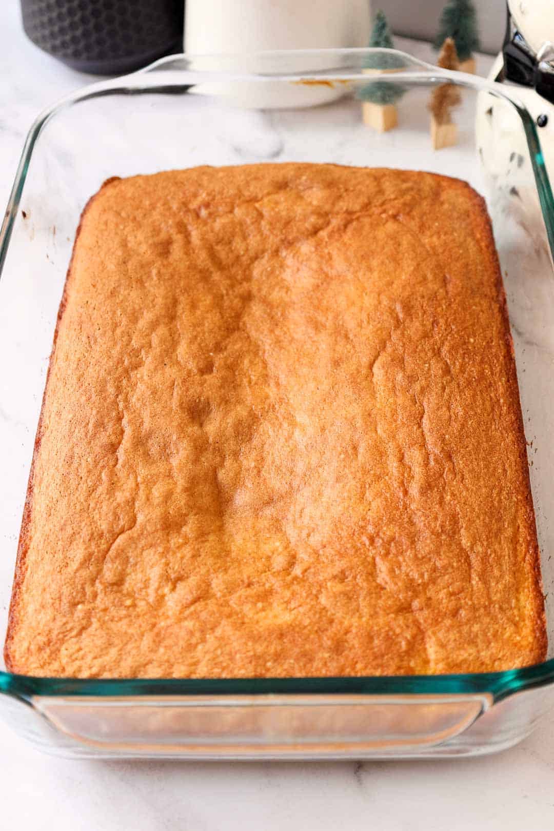 A golden-baked butter cake layer cooling in a glass baking dish.