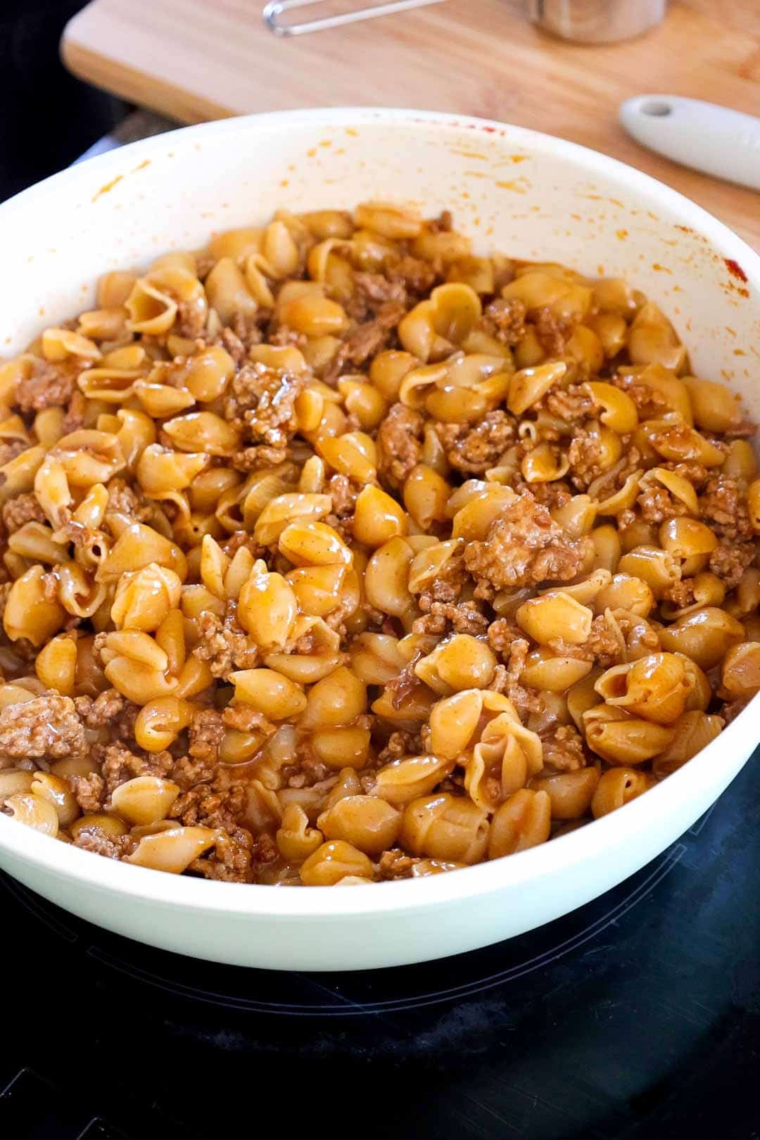 Pasta shells and seasoned beef just combined in the skillet before the cheese is fully melted.