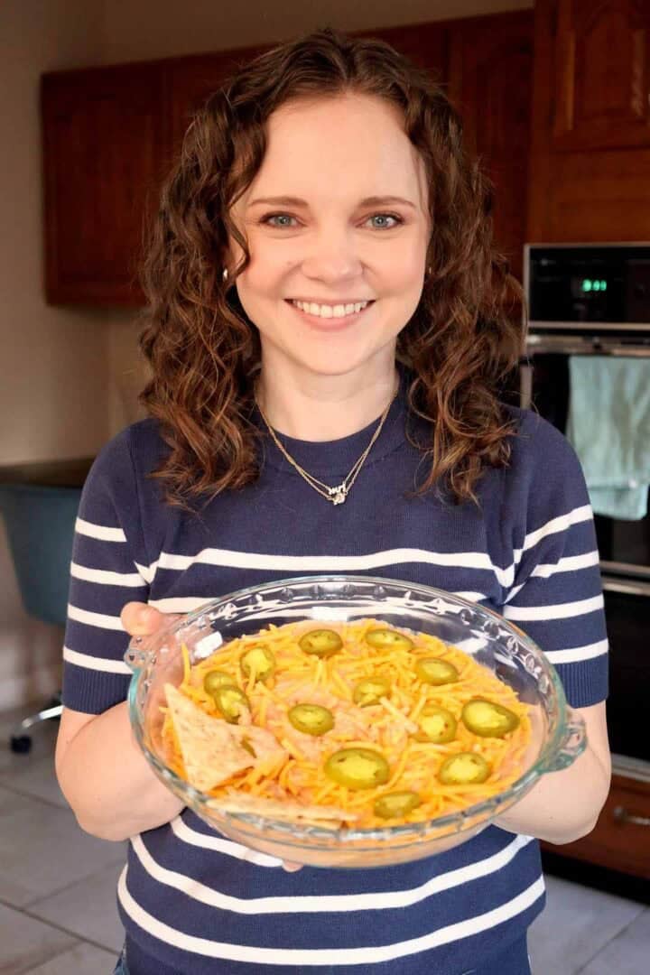 Kelsey Smith holding a glass pie dish of creamy salsa dip.