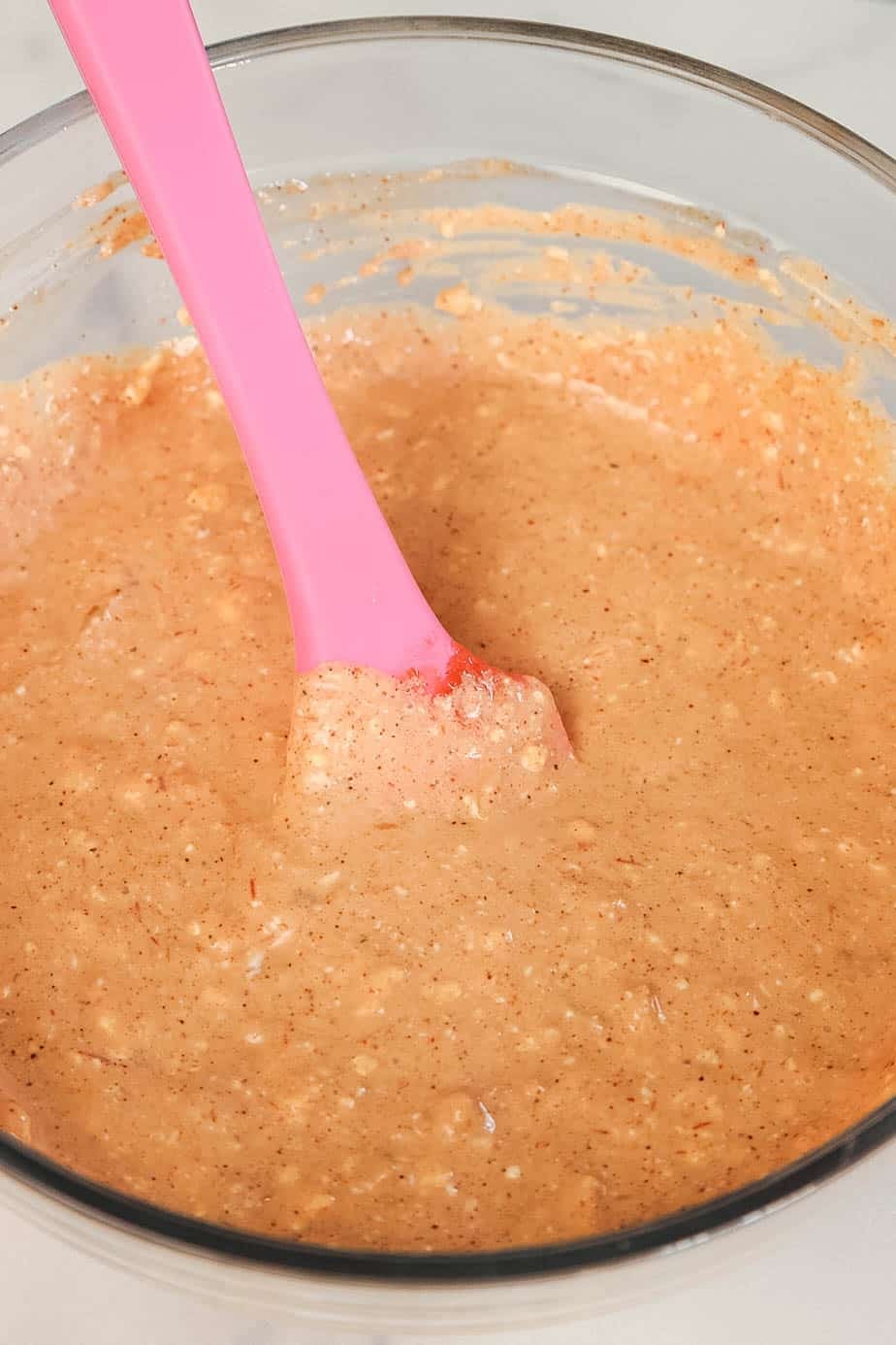 A glass bowl of cream cheese, salsa, and taco seasoning mixture being stirred with a spatula.