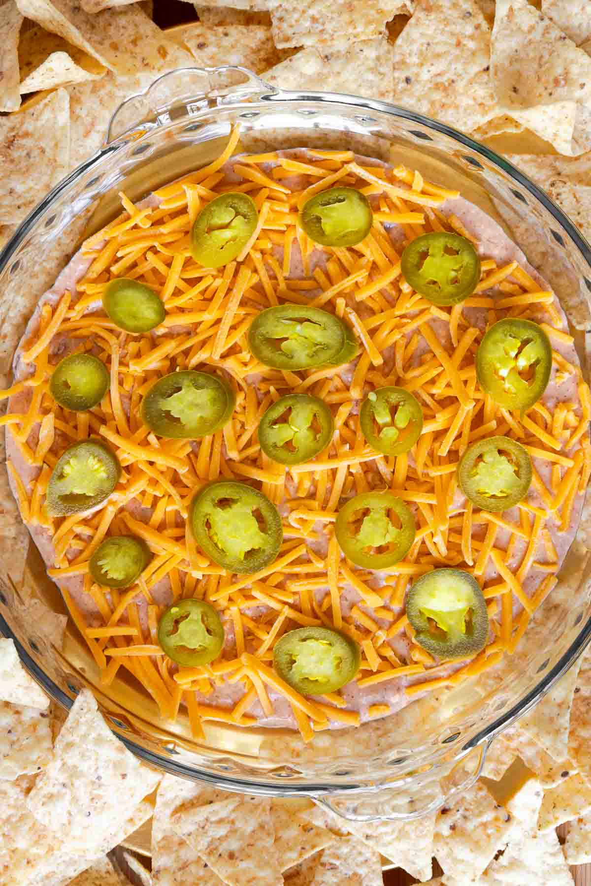 Overhead view of the finished cream cheese and salsa dip garnished with cheese and jalapeños, surrounded by tortilla chips.