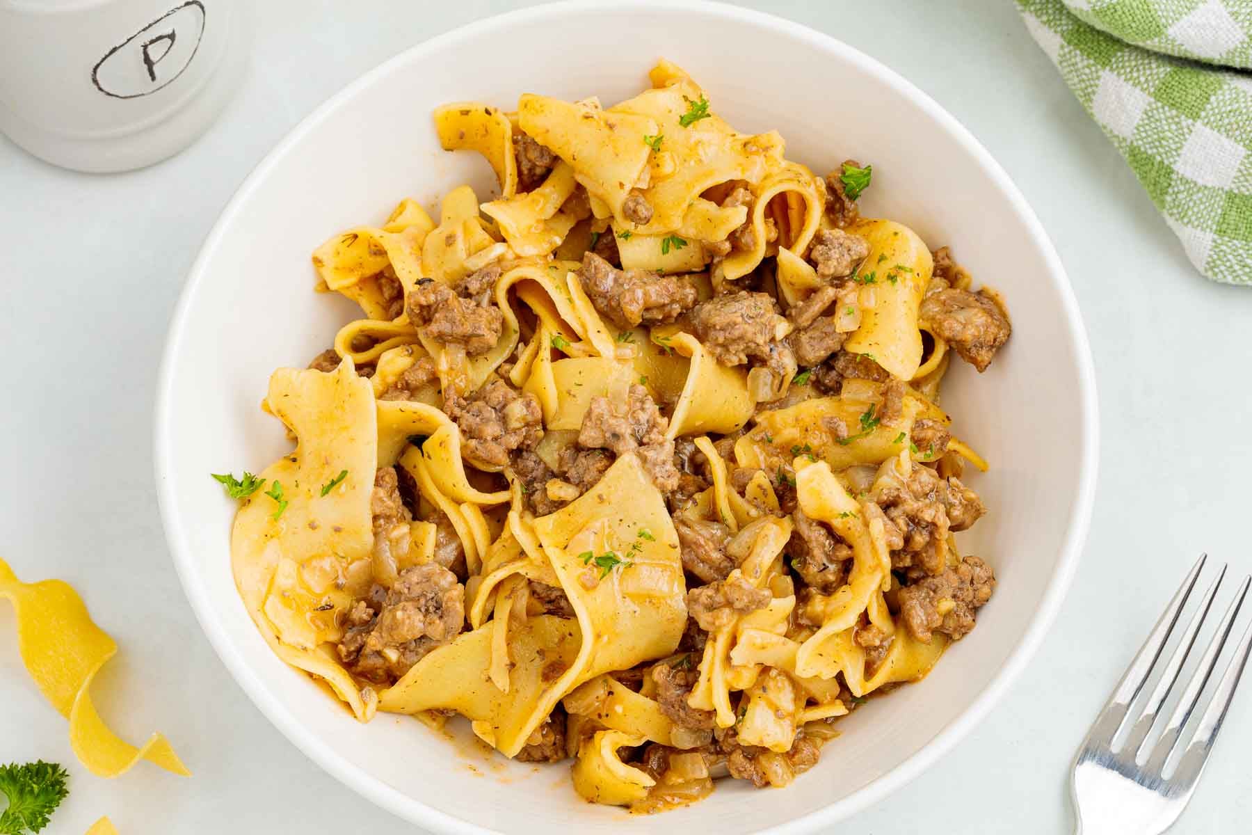 Close up of ground beef egg noodles served in a white bowl.