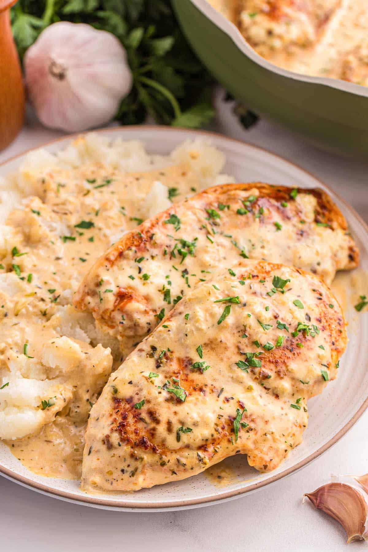 Chicken breasts covered in creamy garlic sauce plated with mashed potatoes.