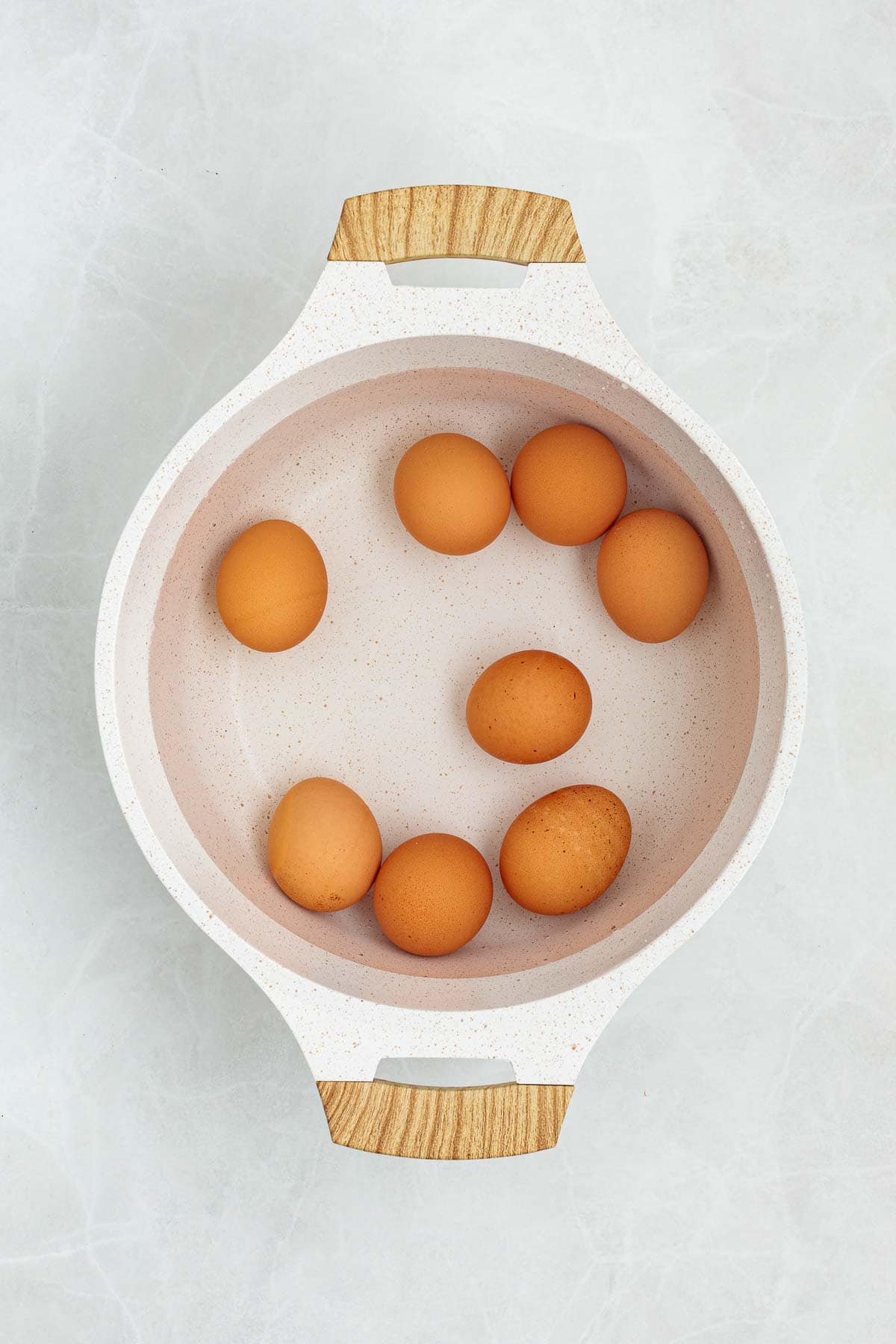 Eggs placed in a pot of water ready to be boiled, shown from above as part of the preparation process for egg salad.