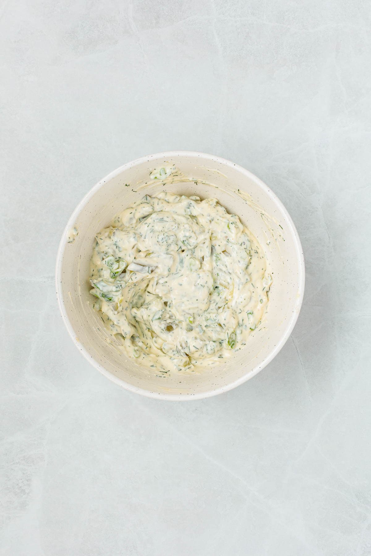 Creamy mixture with chopped pickles, herbs, and green onions stirred into the dressing, showing the base of dill pickle egg salad before adding eggs.
