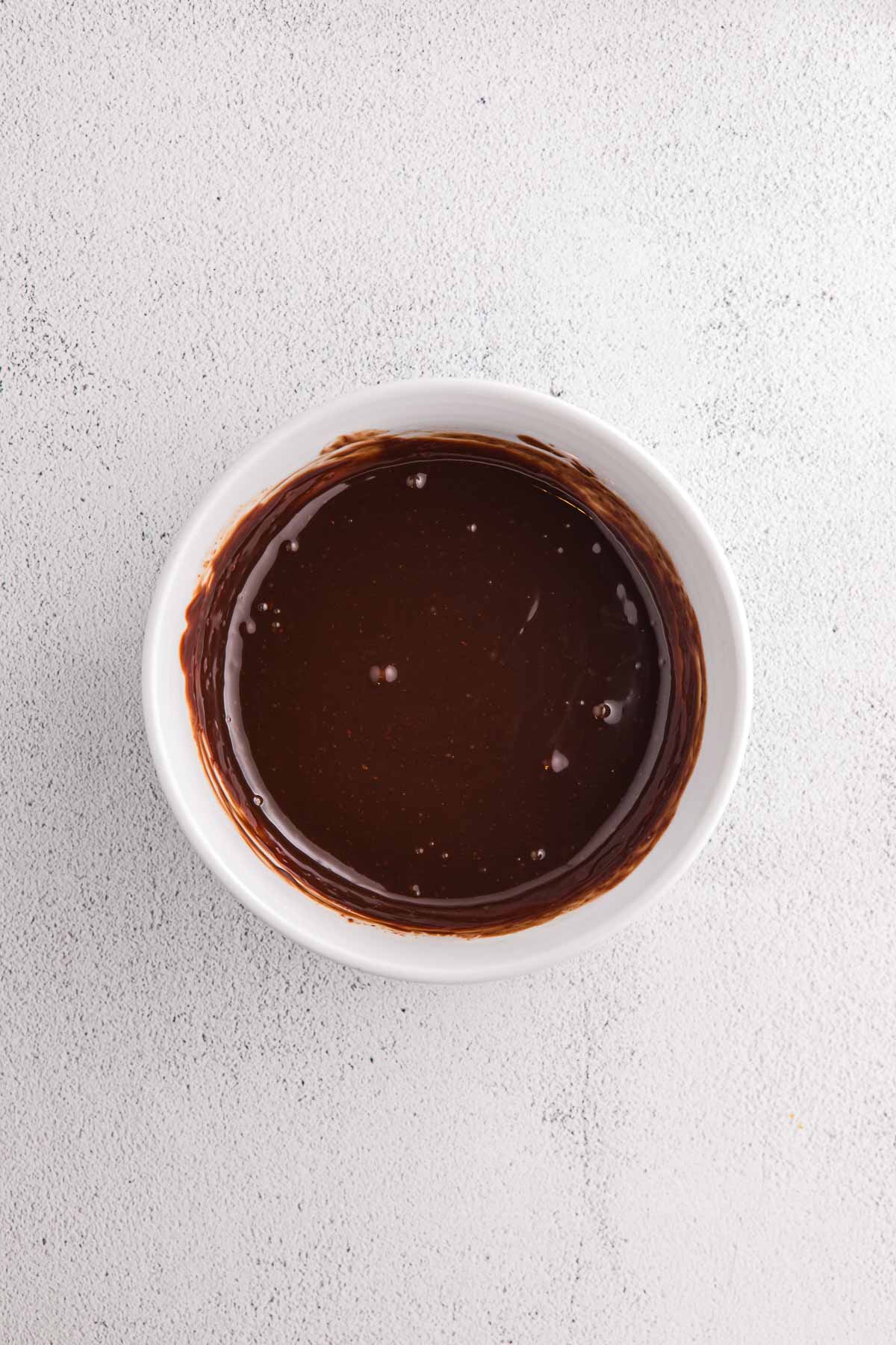 Bowl of melted chocolate prepared for no bake banana split pie.