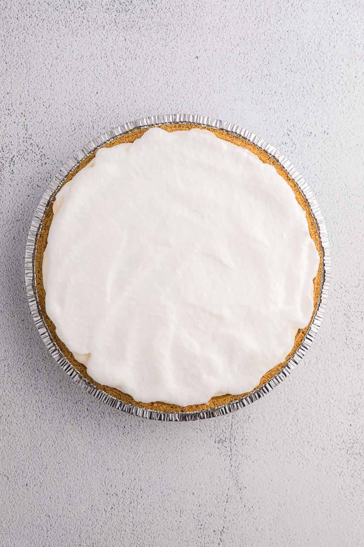 Layer of whipped topping spread over pie filling in a graham cracker crust.