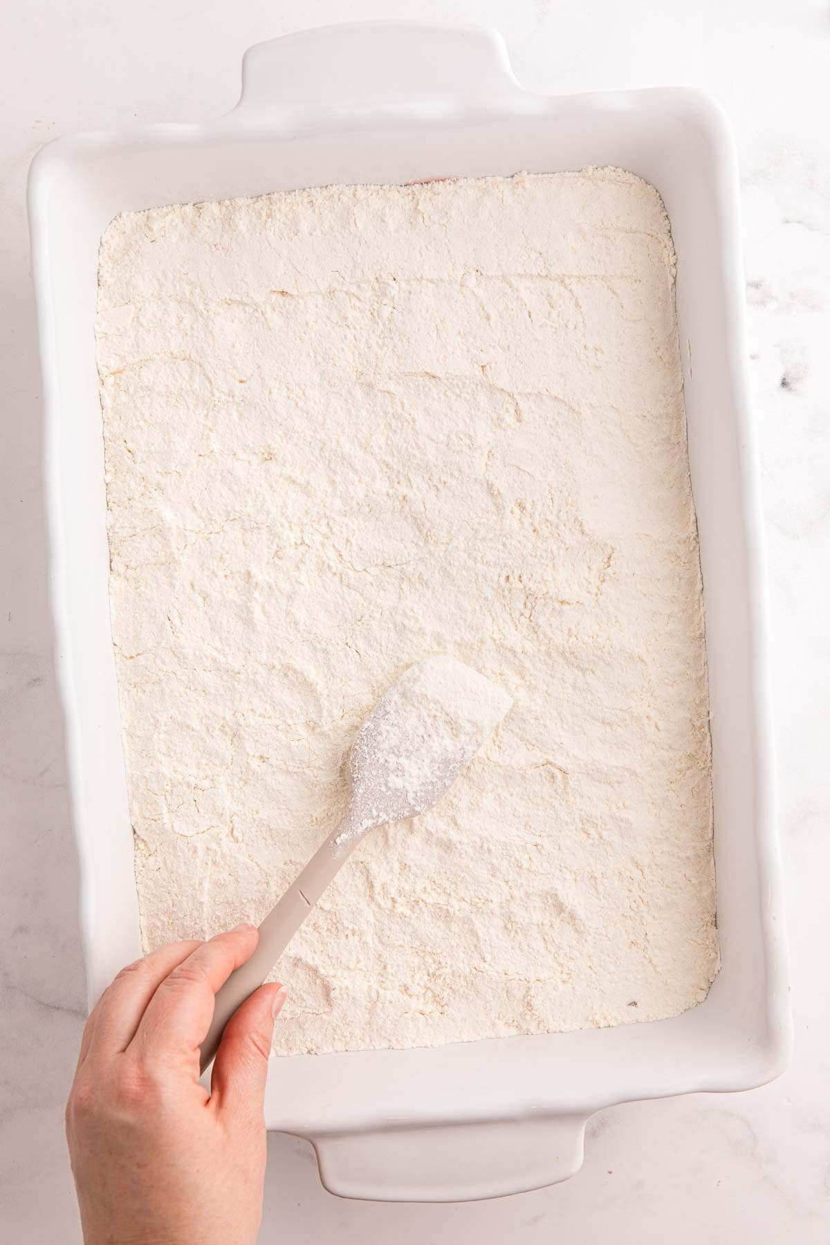 Dry yellow cake mix spread over strawberry pie filling in a 9 by 13 inch baking dish.