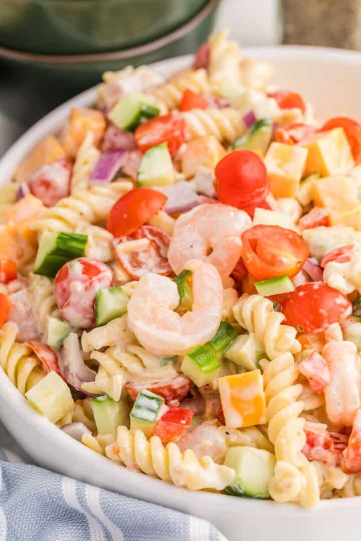 Creamy shrimp pasta salad made with rotini pasta, shrimp, cherry tomatoes, cucumber, red onion, and cheddar cheese coated in a creamy dressing.