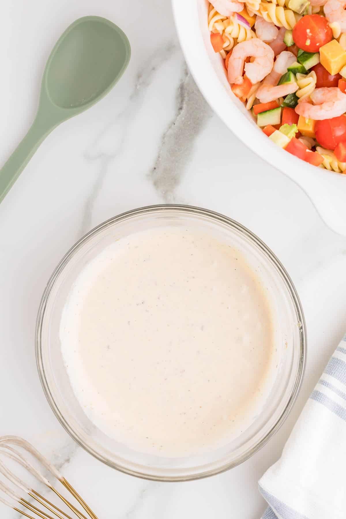 Creamy dressing for shrimp pasta salad made with mayonnaise, Italian dressing, lemon juice, garlic powder, salt, and black pepper whisked until smooth.