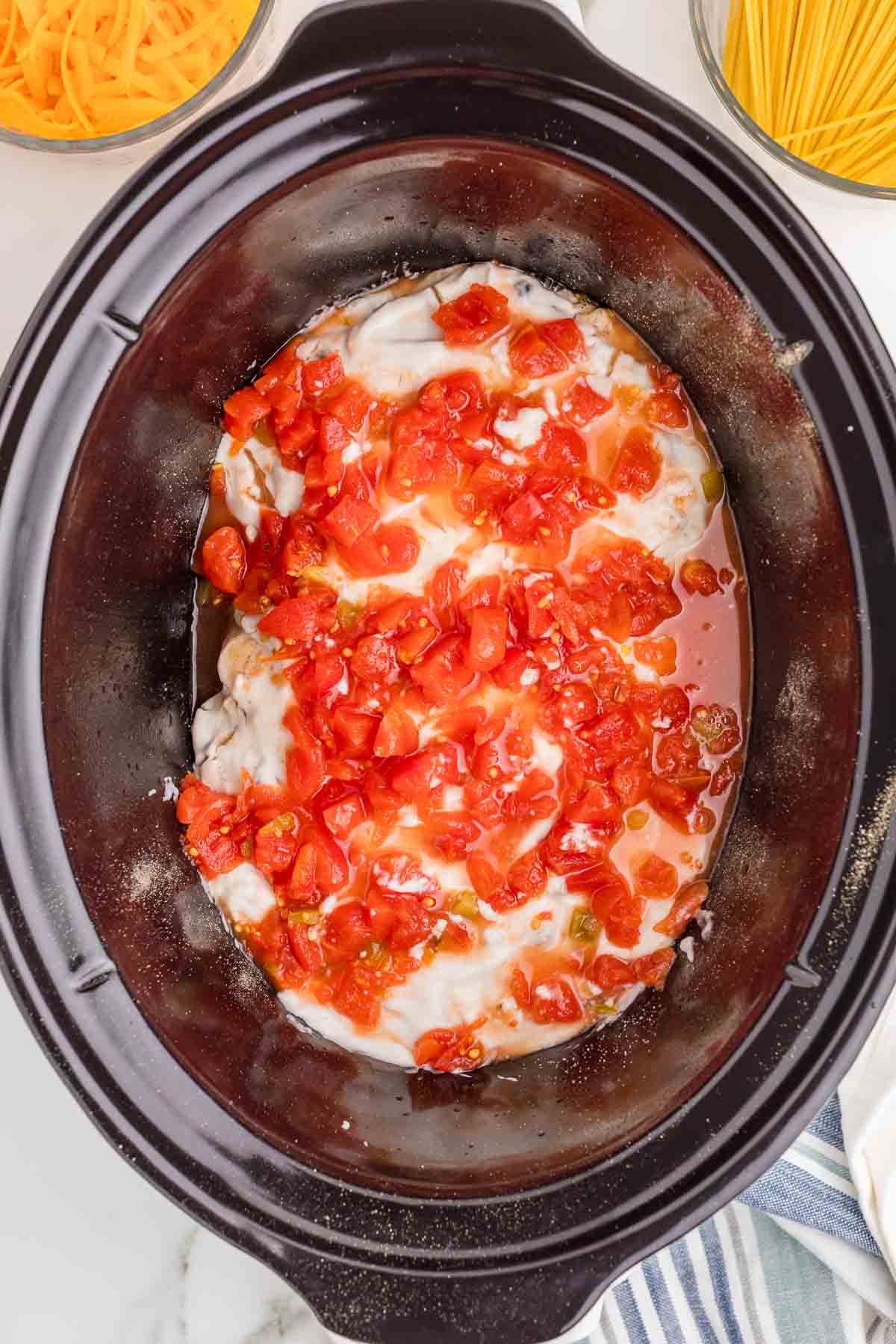 Rotel diced tomatoes and green chilies and cream of mushroom soup layered over the seasoned chicken breasts in the slow cooker without stirring.