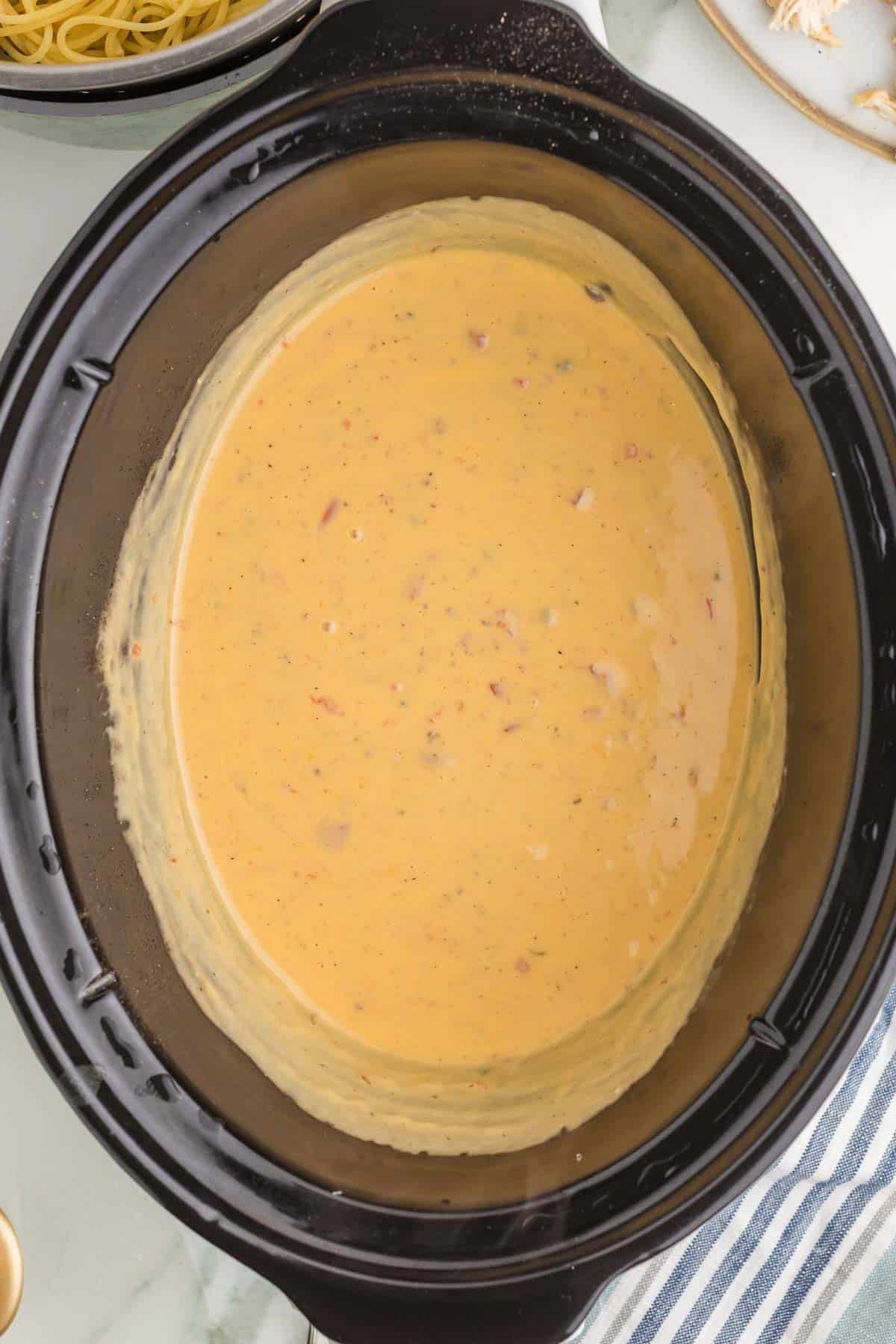 Smooth melted cheese sauce with pieces of tomato and mushroom stirred together in the slow cooker before adding the chicken and spaghetti.
