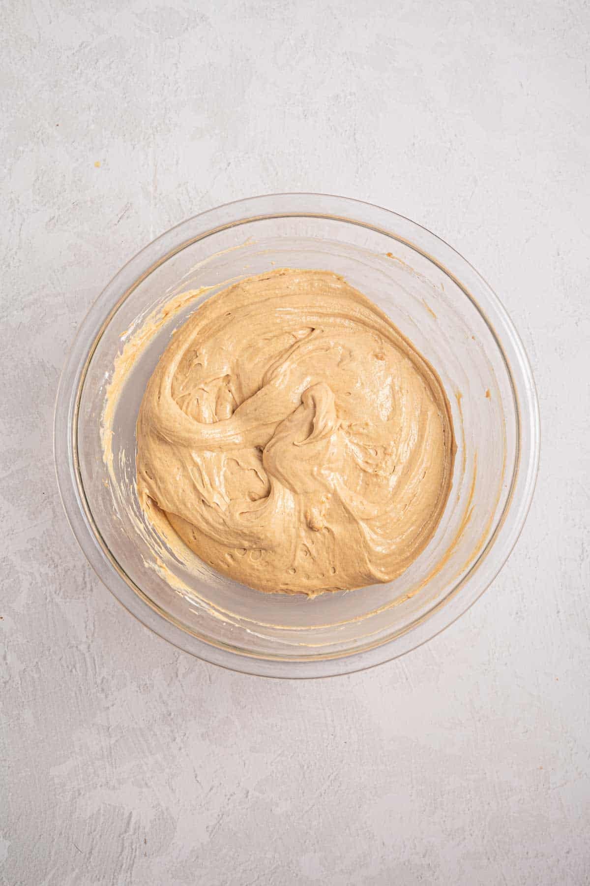 Smooth light brown cookie butter and cream cheese mixture in a mixing bowl. The filling has been beaten until evenly combined before the whipped topping is folded in.