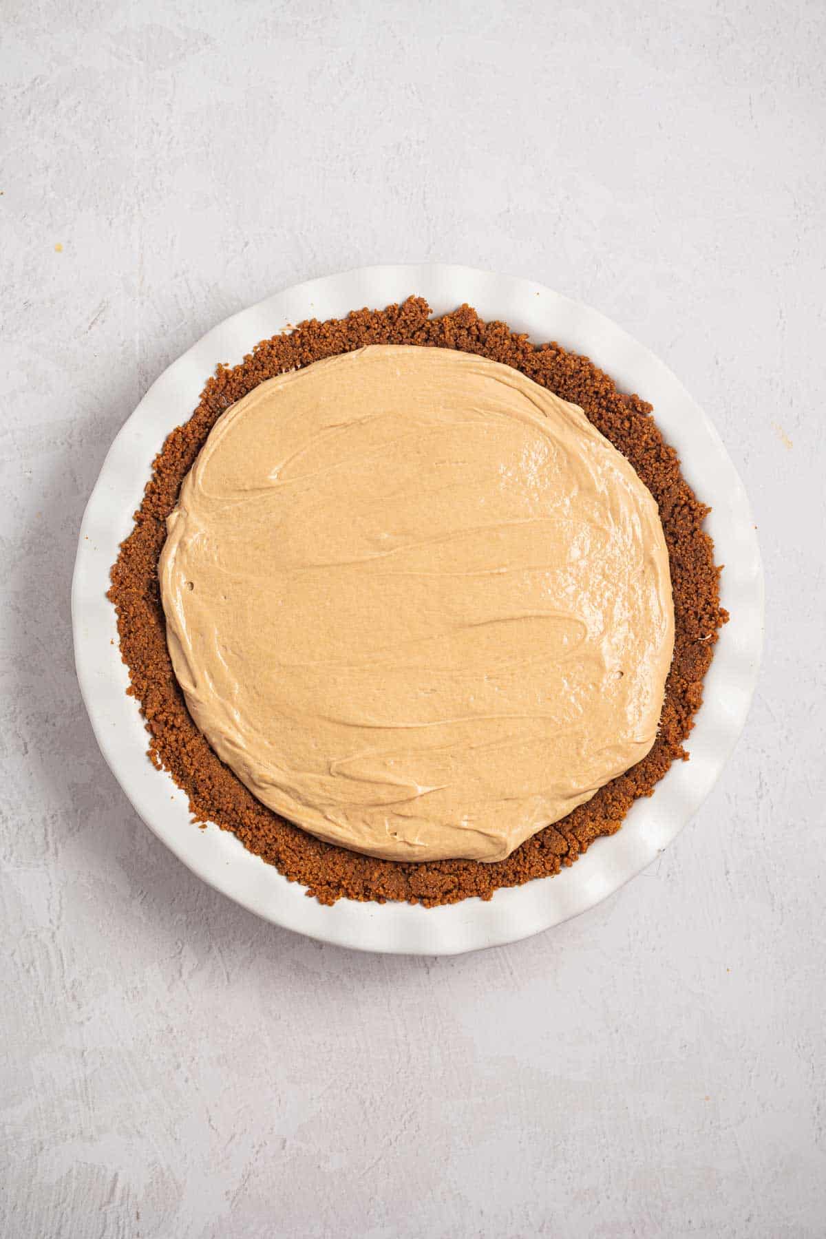 Creamy cookie butter pie filling spread evenly inside the chilled Biscoff cookie crust. The filled pie is ready to be refrigerated until firm and set.