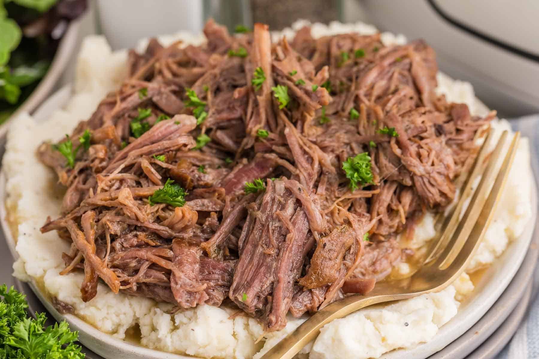 Tender shredded Mississippi pot roast served over a thick layer of mashed potatoes.