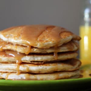 Stack of banana pancakes with syrup drizzled on top.