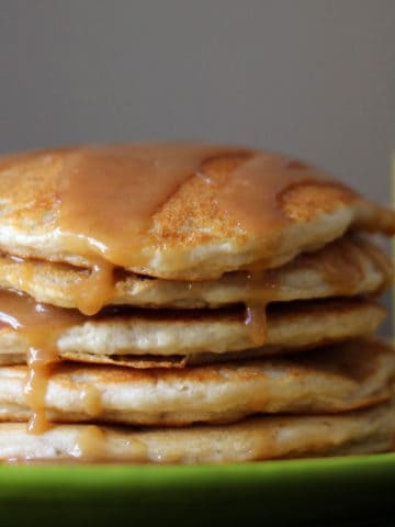 Stack of banana pancakes with syrup drizzled on top.