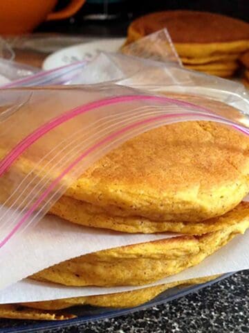 Pancakes stacked in a food storage bag with parchment paper between each pancake.