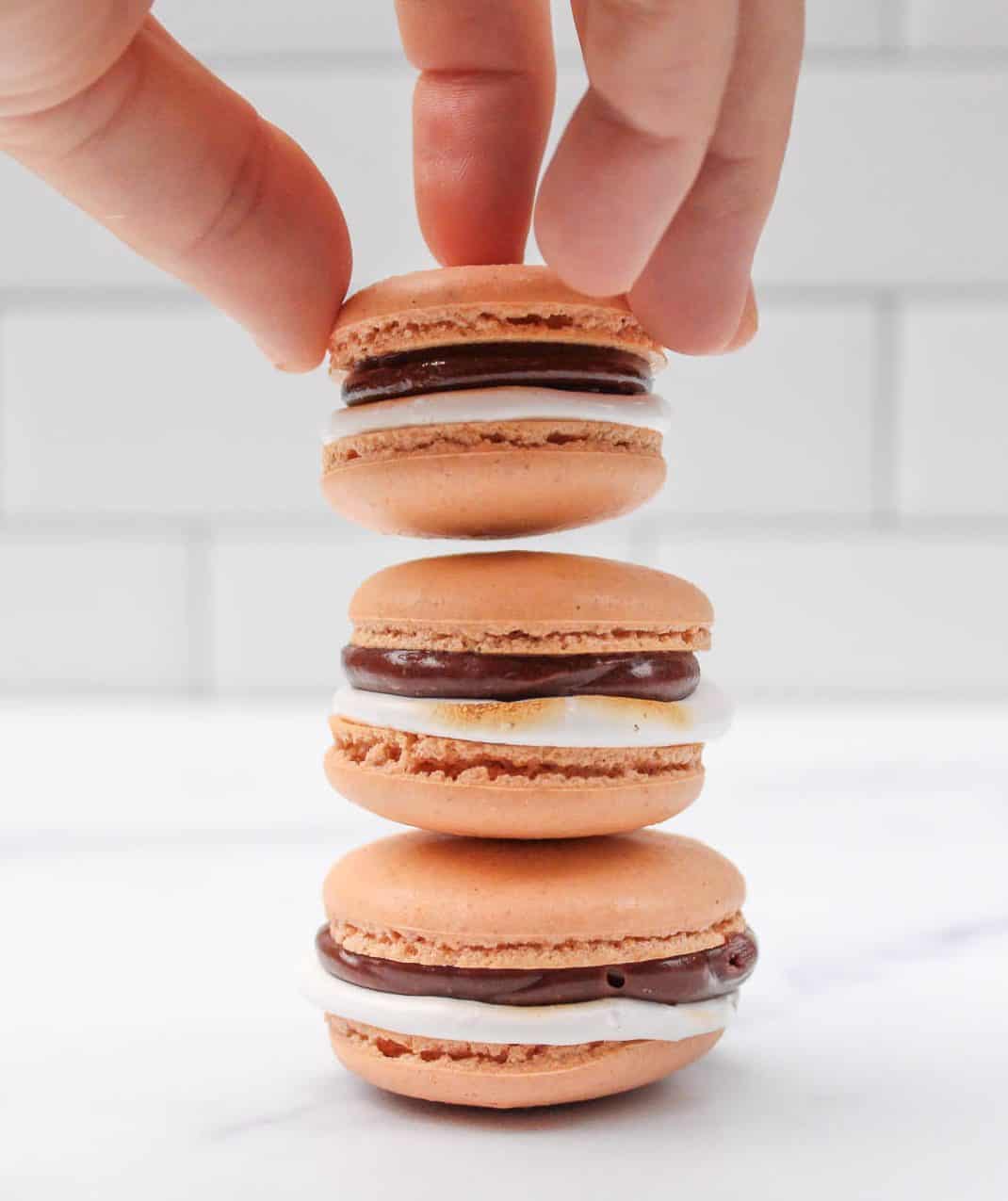 A hand stacking macarons.