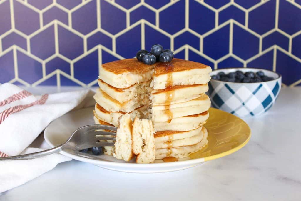 Stack of pancakes with a slice taken out.