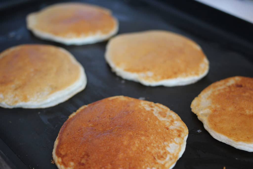 Pancakes cooking on the griddle.