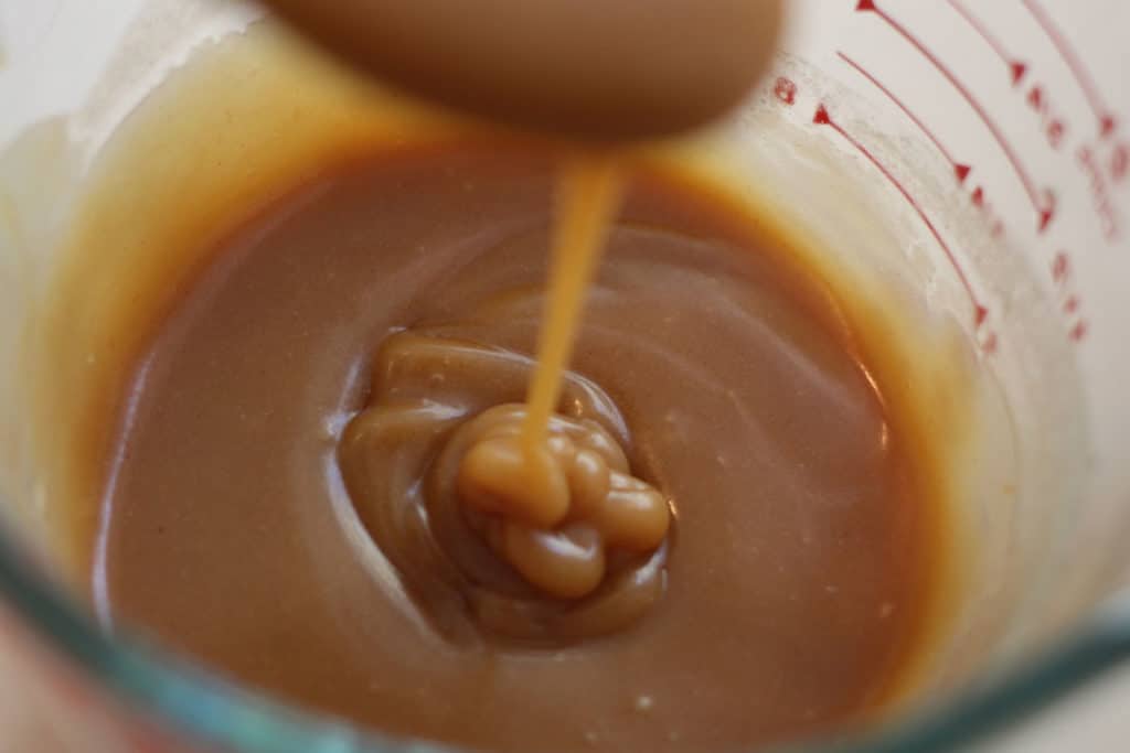 Peanut butter pancake syrup dripping off of a spoon.