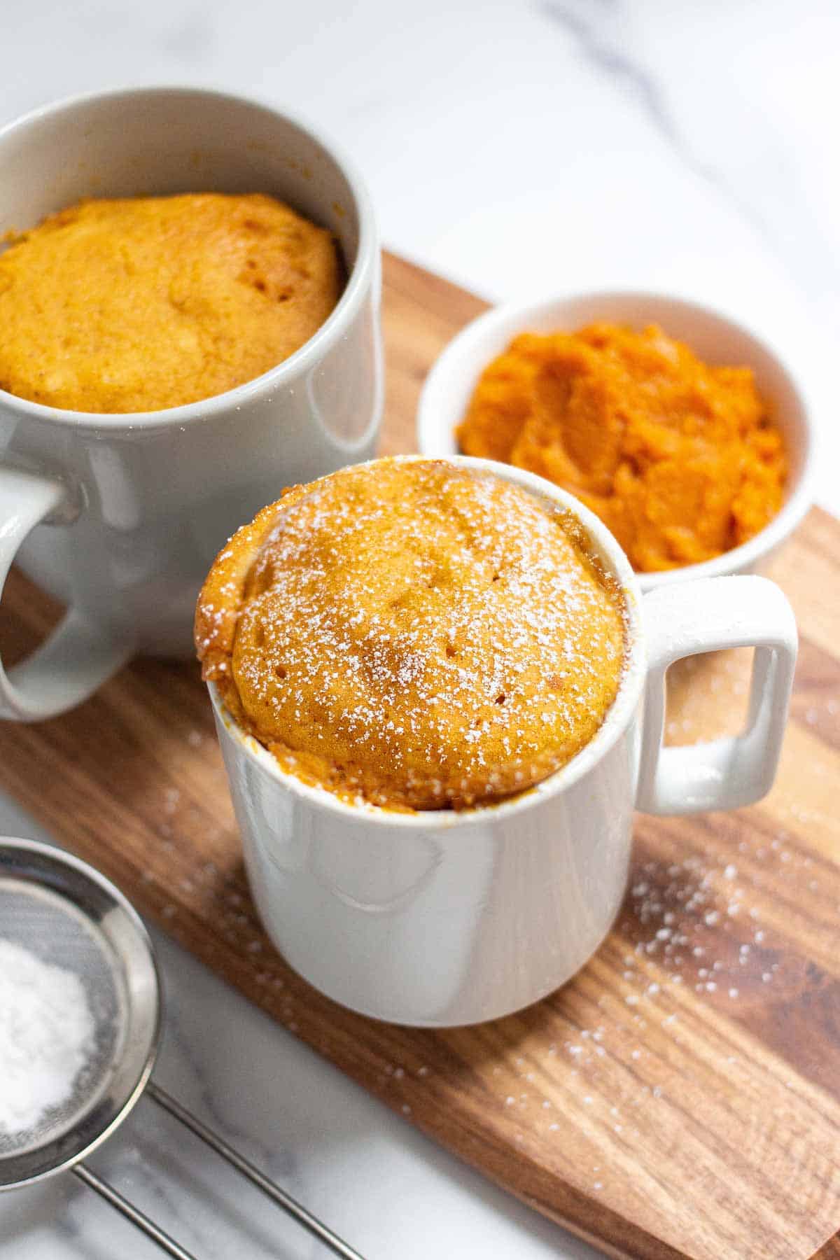 Pumpkin Mug Cake in a 16oz mug with room at the top and in a 12oz mug with cake above the edge of the cup.