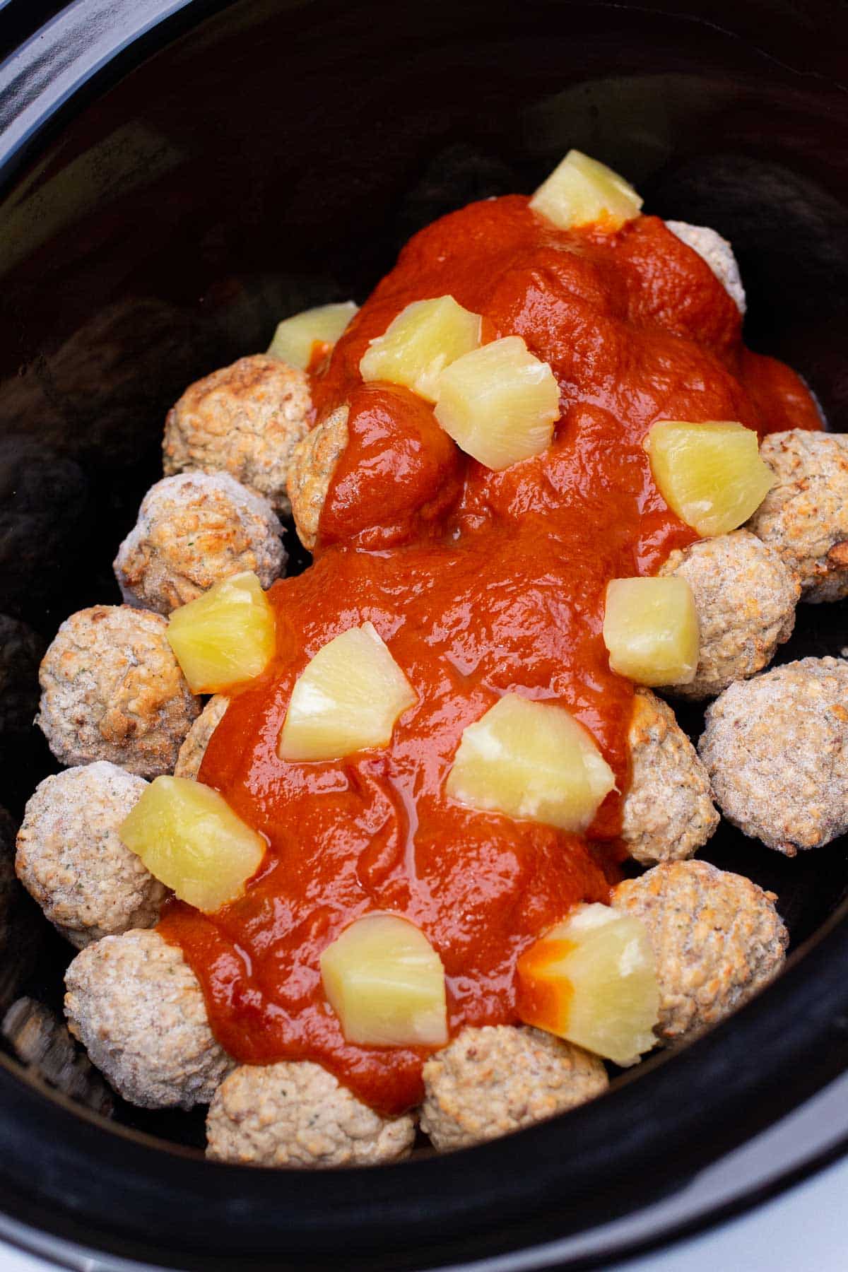 Frozen meatballs, sloppy joe sauce, and canned pineapple layered in the slow cooker.